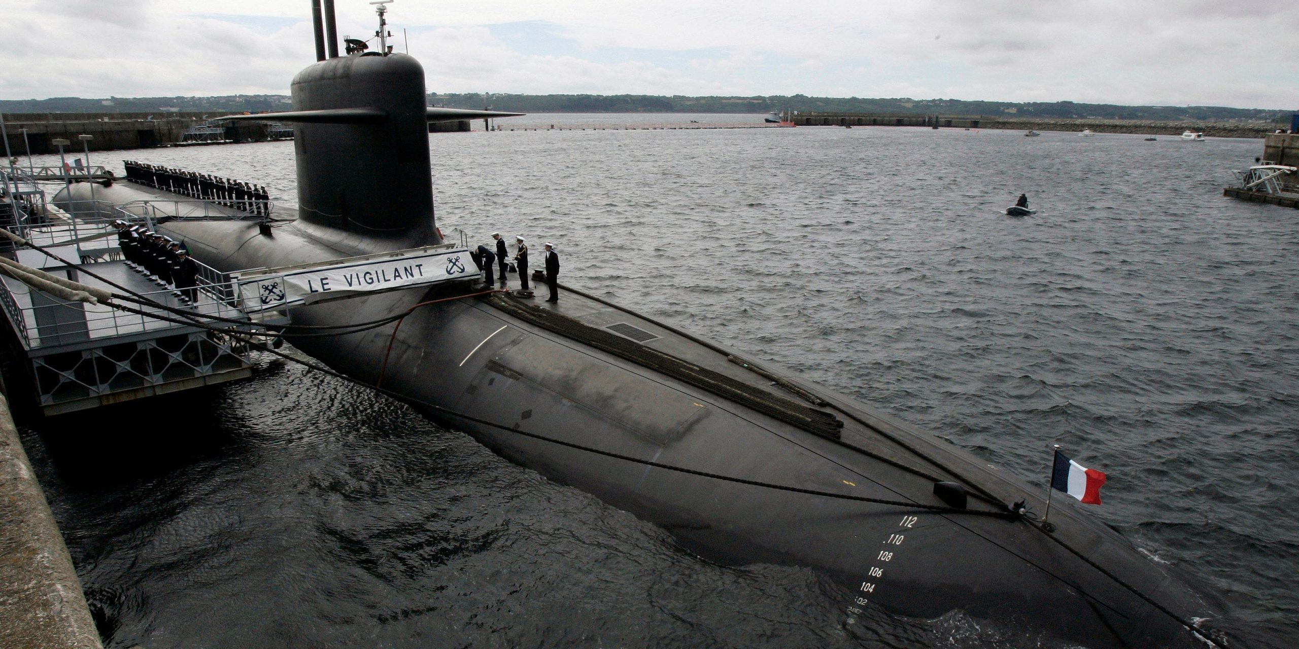 FILE - In this July 13, 2007 file photo, French Marine officers wait atop "Le Vigilant" nuclear submarine at L'Ile Longue military base, near Brest, Brittany. Stealthily cruising the ocean deeps, deliberately hiding from the world now in turmoil, the crews of nuclear-armed submarines may be among the last pockets of people anywhere who are still blissfully unaware of how the coronavirus pandemic is turning life upside down. The new coronavirus causes mild or moderate symptoms for most people, but for some, especially older adults and people with existing health problems, it can cause more severe illness or death. (AP Photo/Francois Mori, Pool, File)