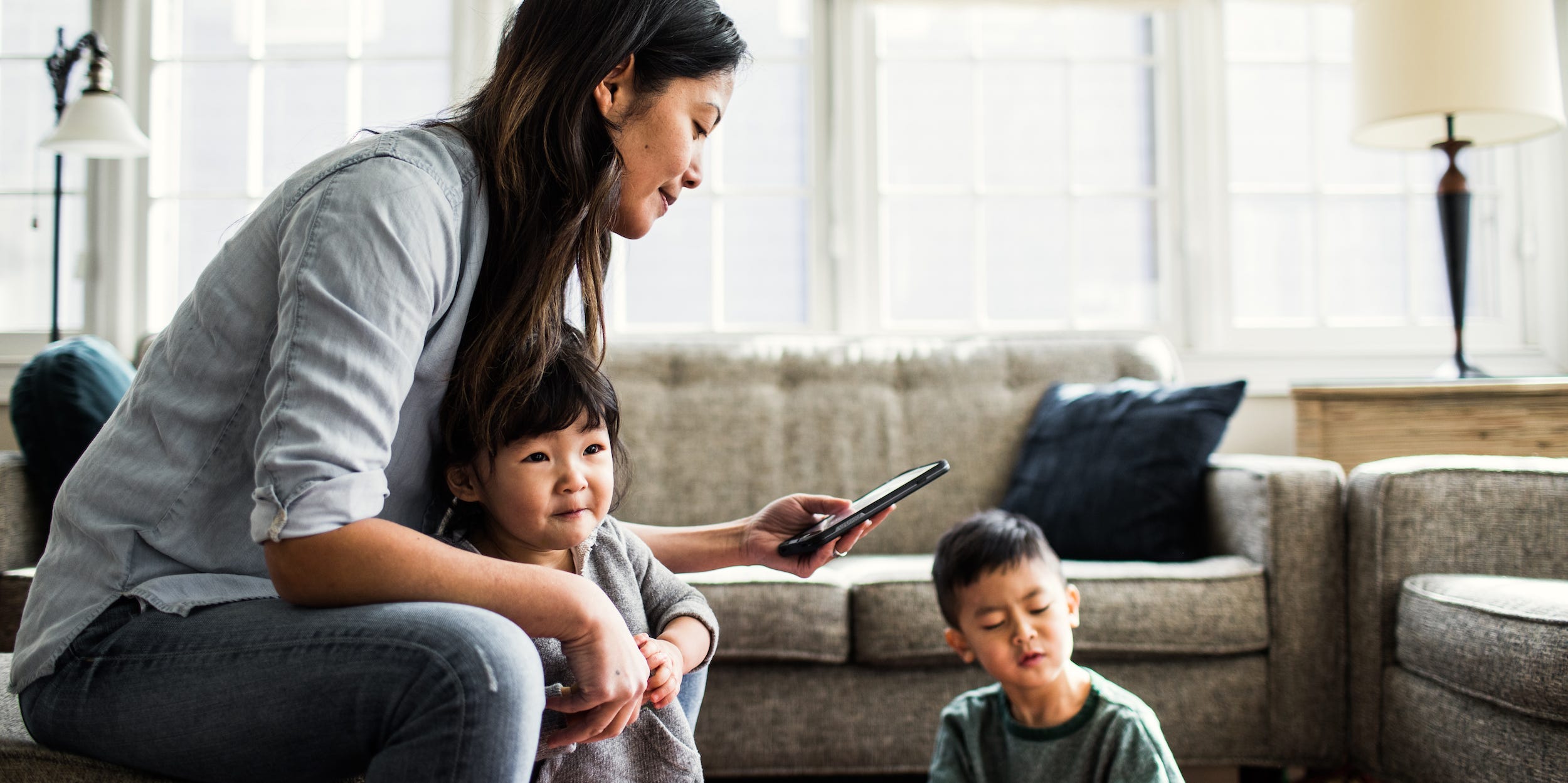 mother using phone with young children at home