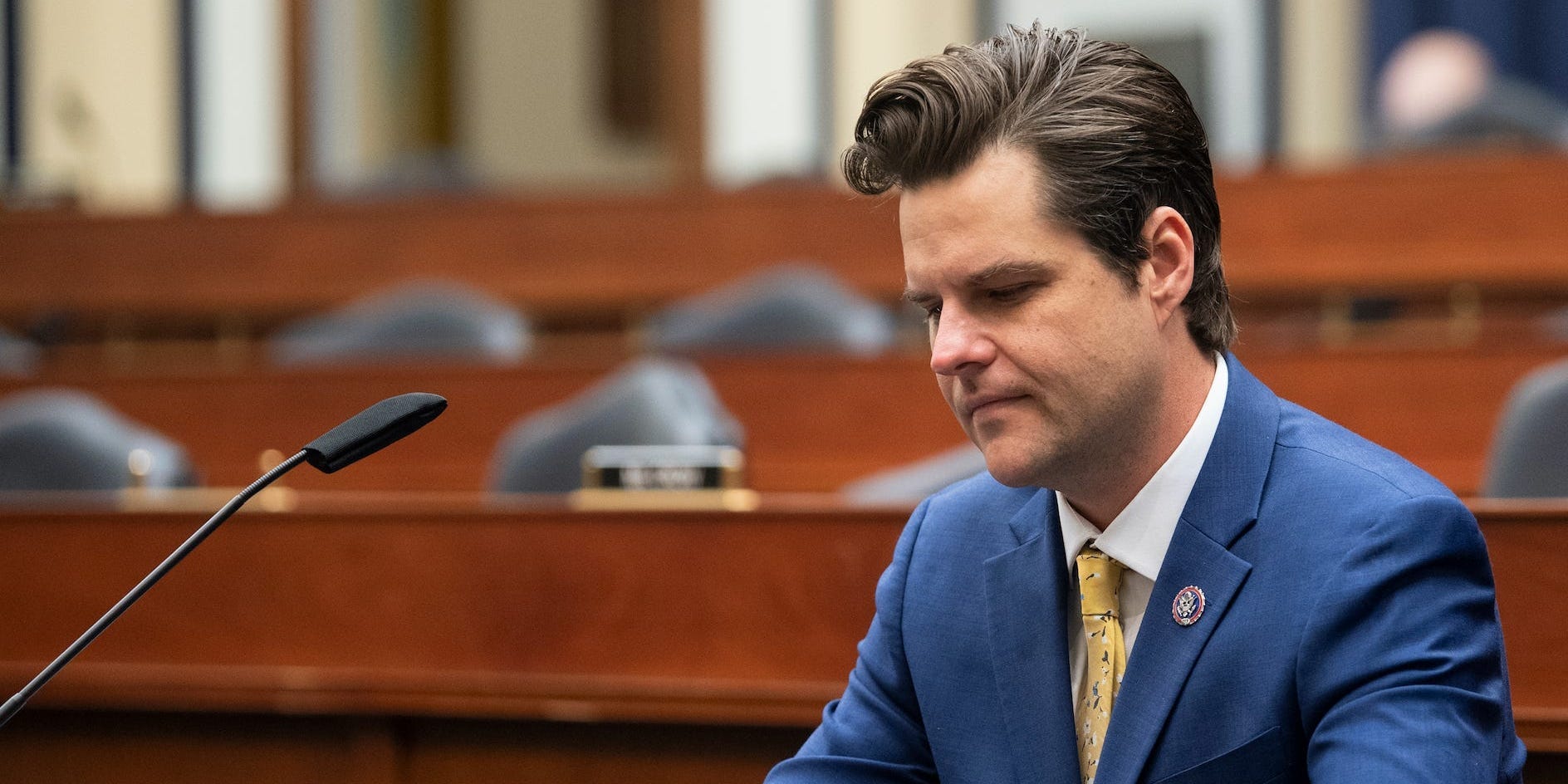 Florida Congressman Matt Gaetz looks at his phone in an empty hearing room.