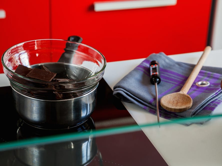 Ingredients and tools needed to temper chocolate on a kitchen counter.