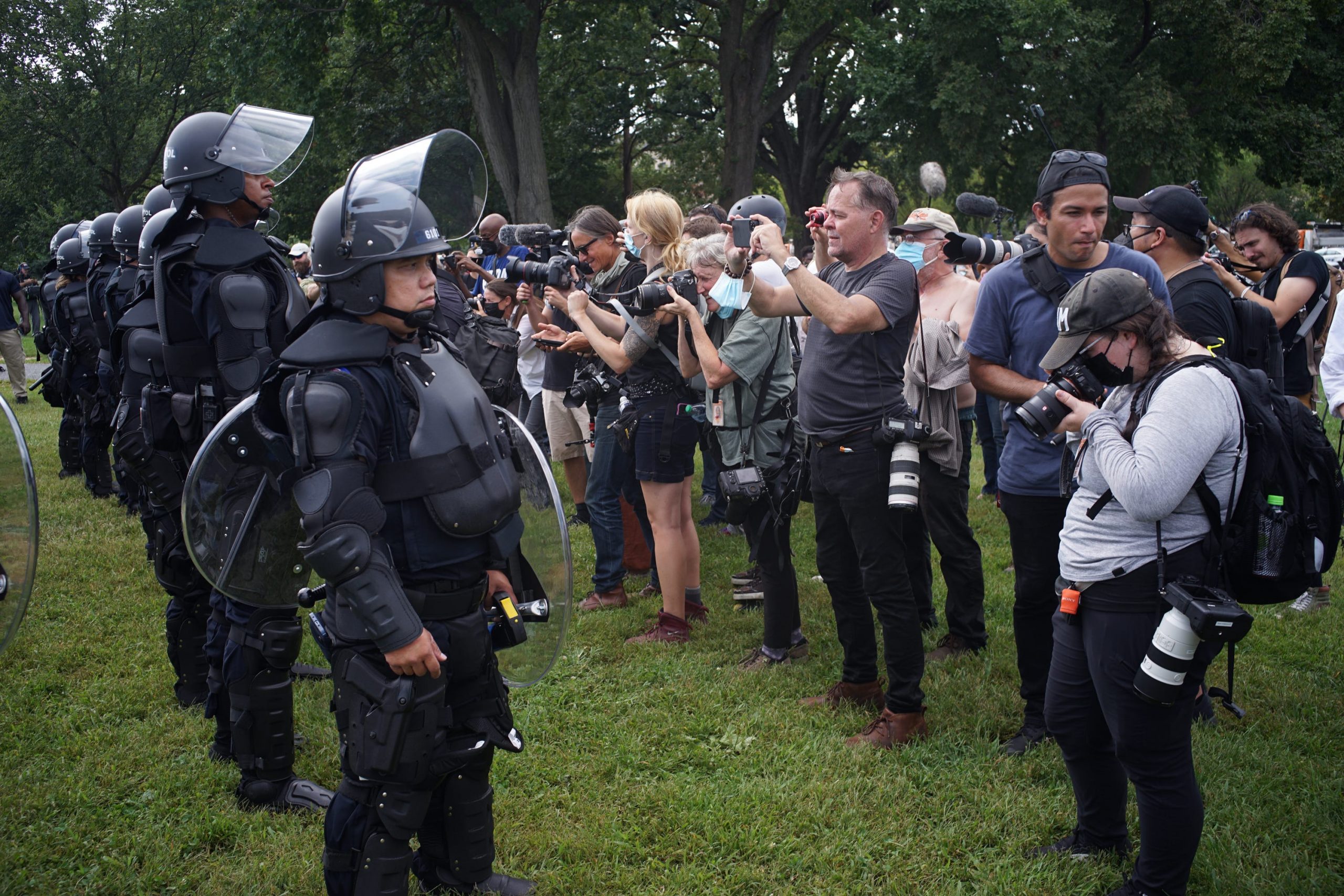Police face a row of photographers