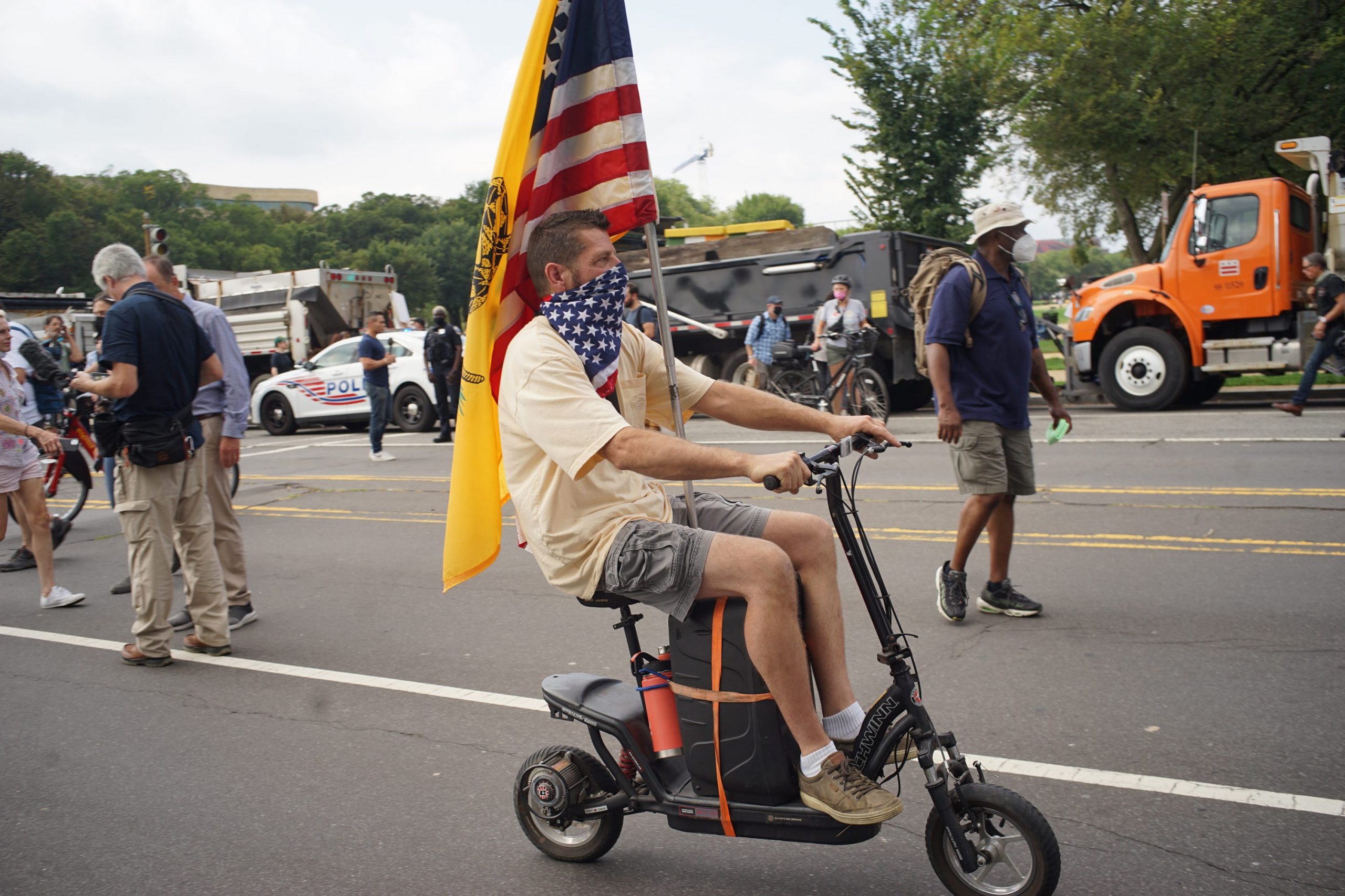A man on a scooter with an American flag.