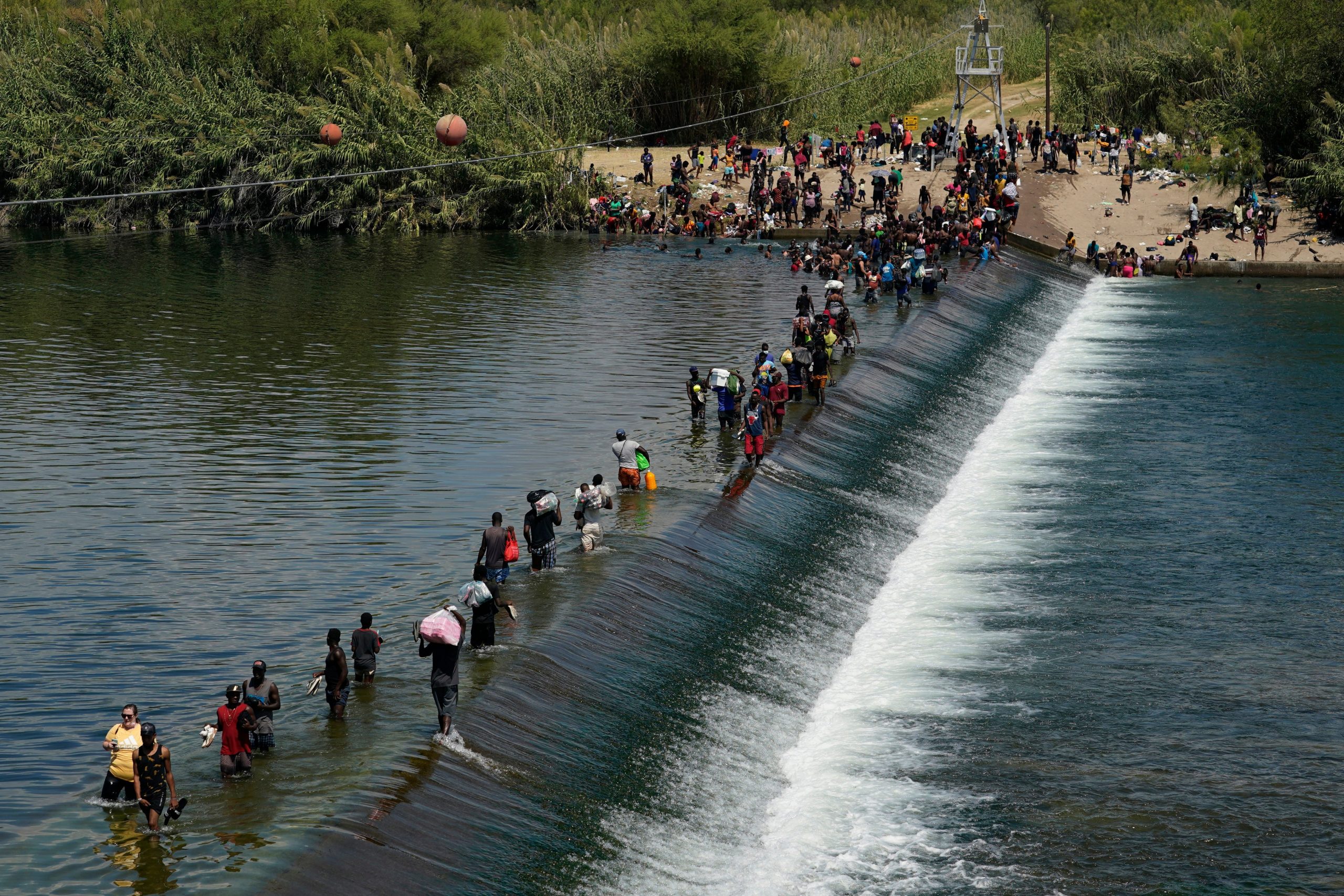 Haitian migrants use a dam to cross into the United States from Mexico, Saturday, Sept. 18, 2021, in Del Rio, Texas.