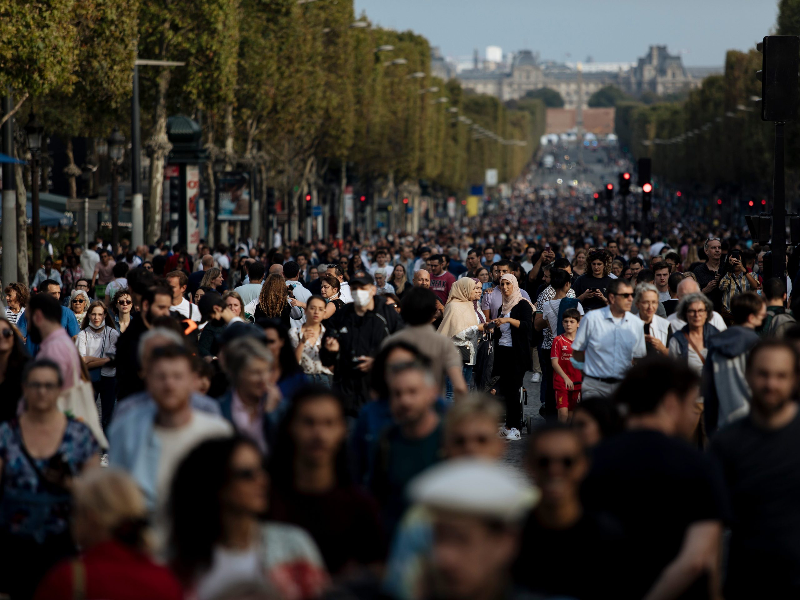 People walk along the Champs Elysees Avenue, Paris, during the "day without cars", with the Arc de Triomphe in the background, Sunday, Sept. 19, 2021.