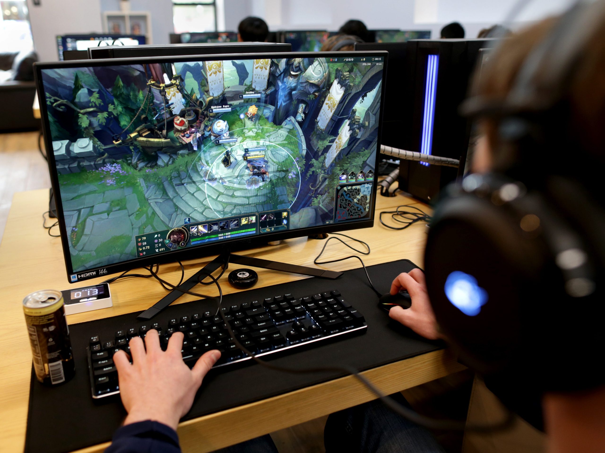 A person sitting at a desk playing League of Legends on a computer