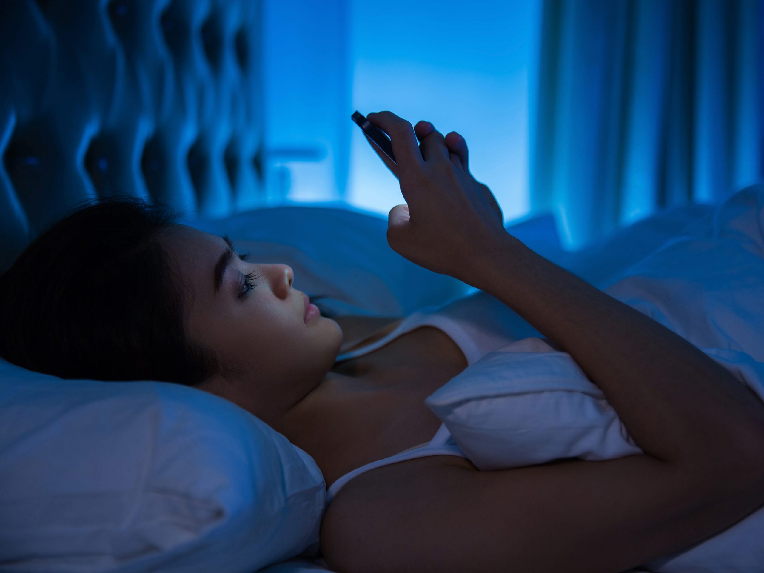 Woman in bed looking at her phone
