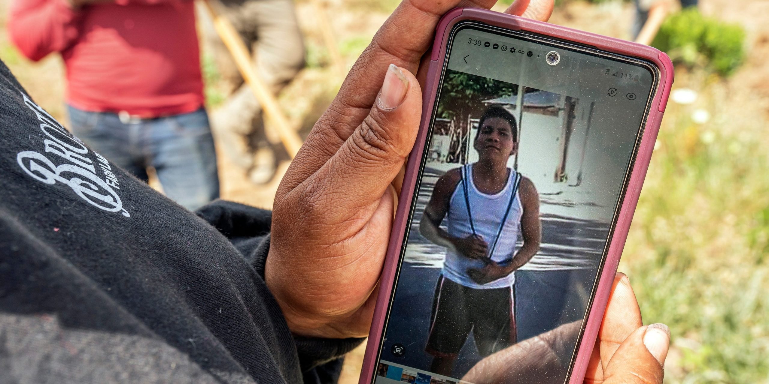 Person holding phone showing photo of deceased worker.