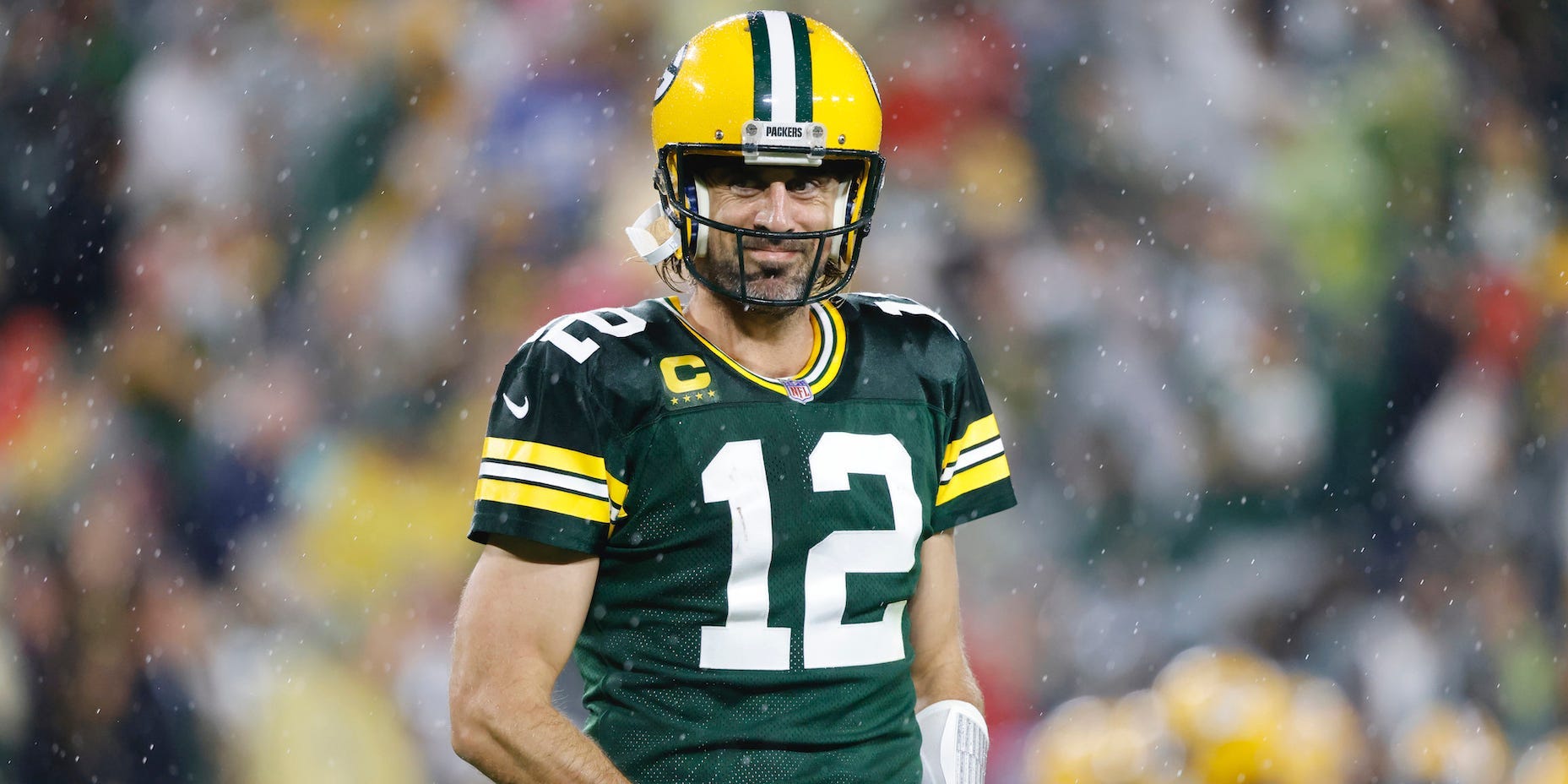 Aaron Rodgers smiles with his hands in his hand-warmers.