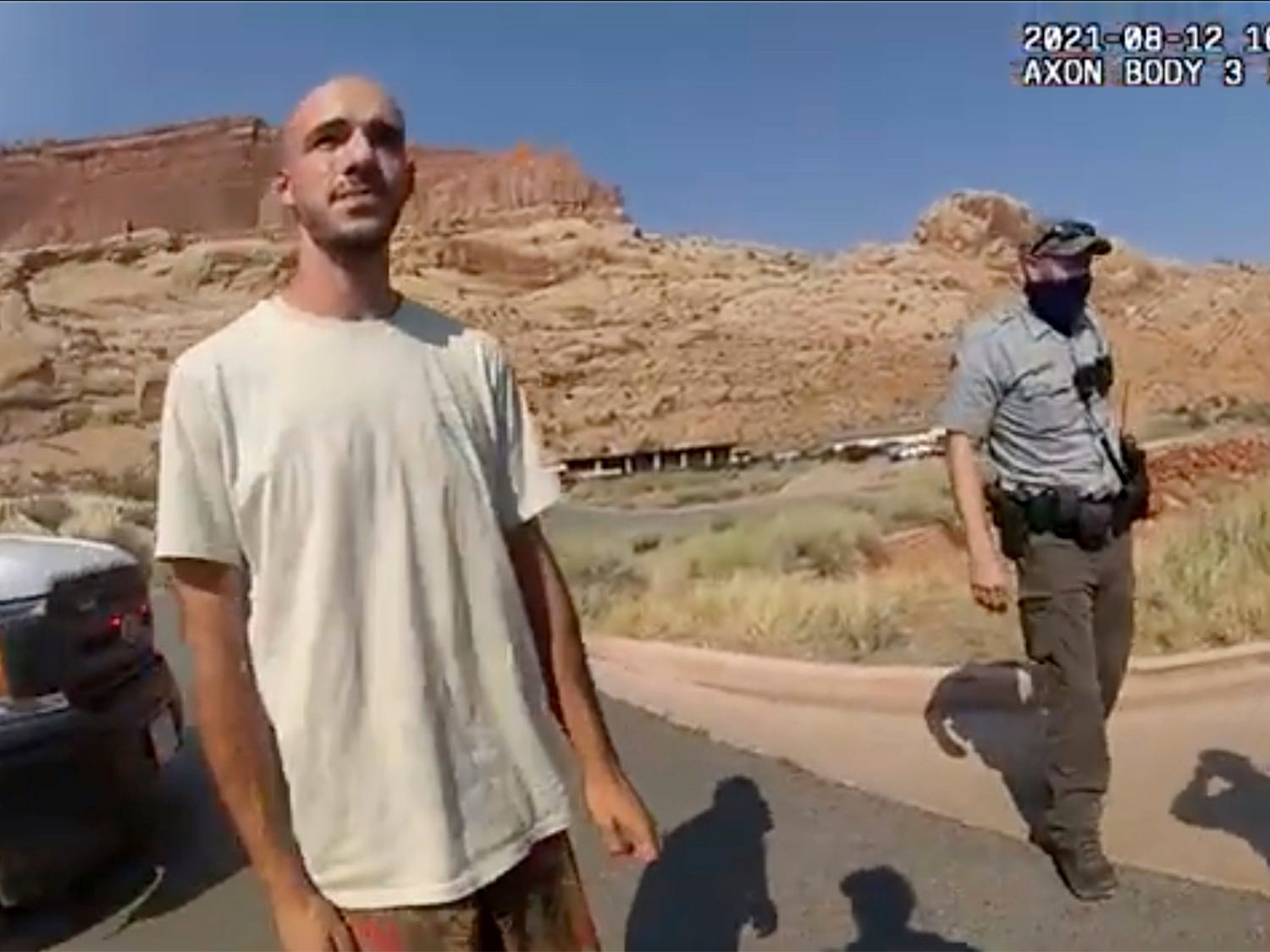 Brian Laundrie in the desert with a cop behind him