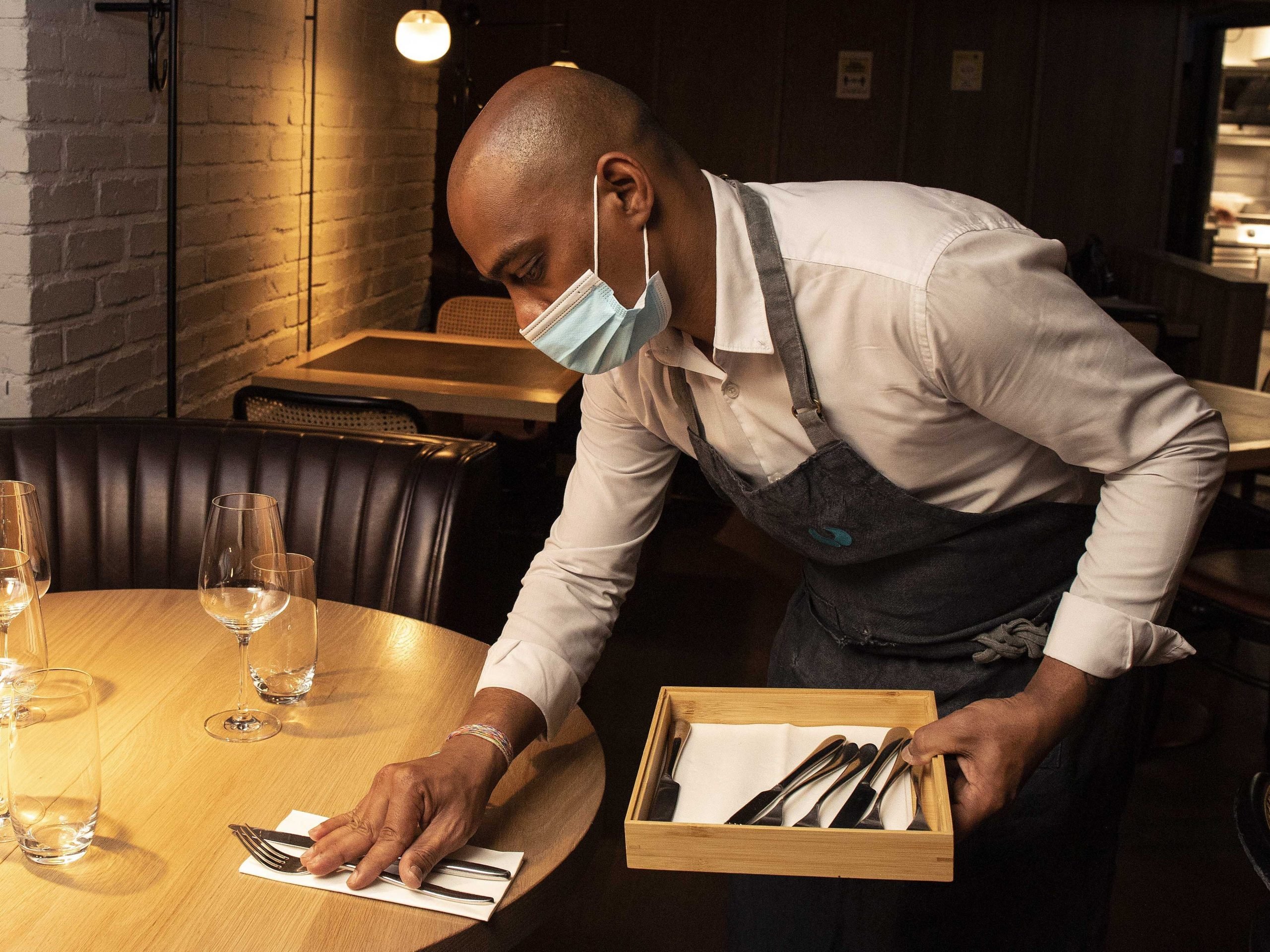 Waiter Niven Bodi Reddy sets a table inside the Ely wine Bar, on Ely place in Dublin, where they will reopen for indoor dining on Thursday July 29.