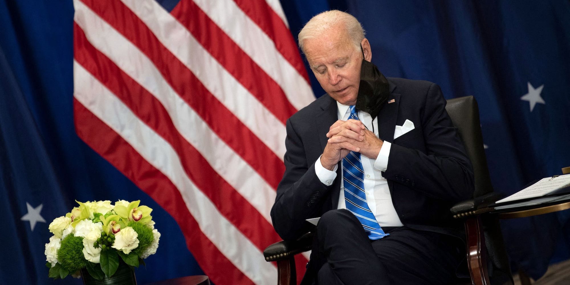 Joe Biden sitting with his hands together and looking at the ground.