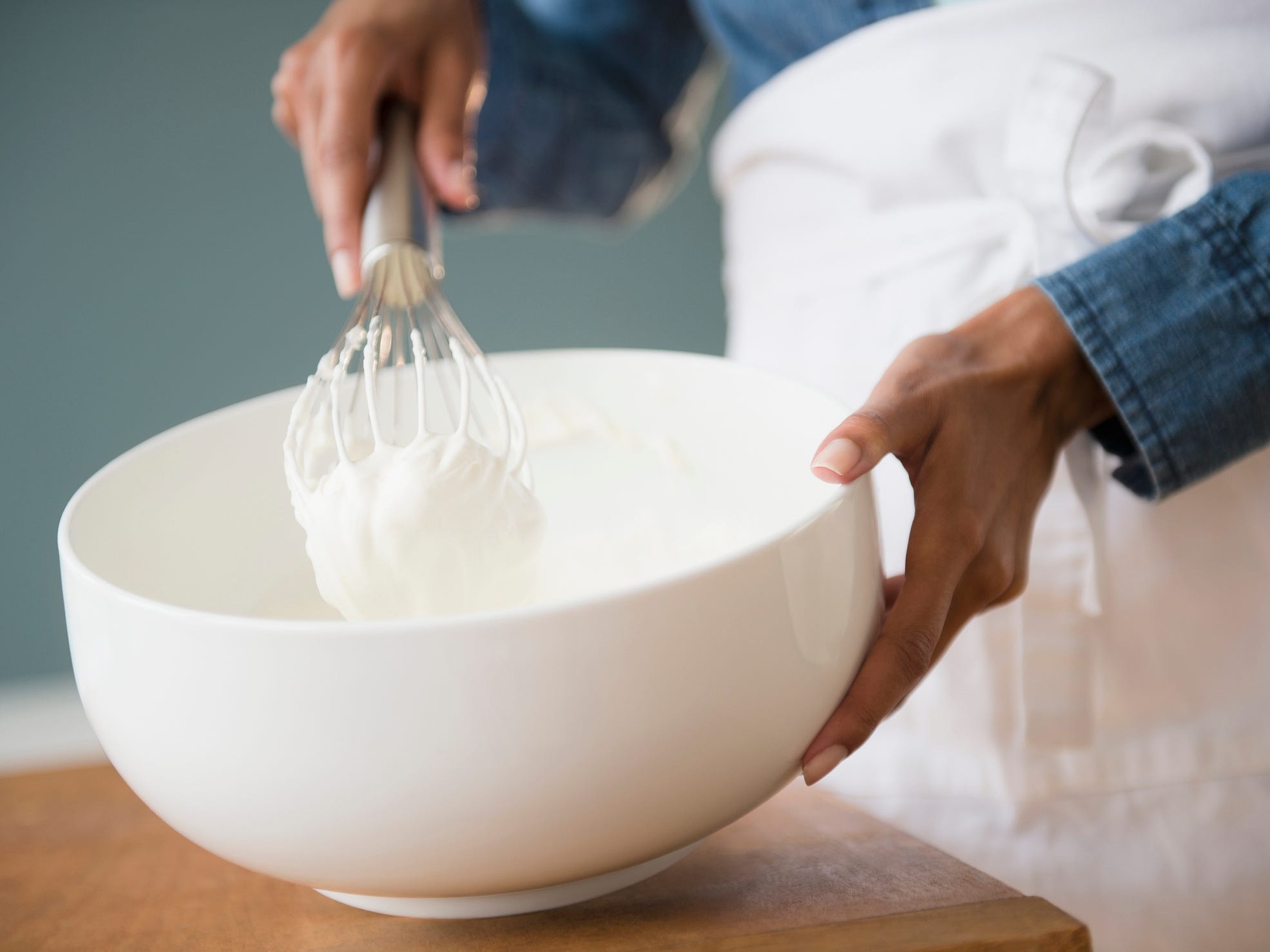 Someone whisking cream in a white bowl.