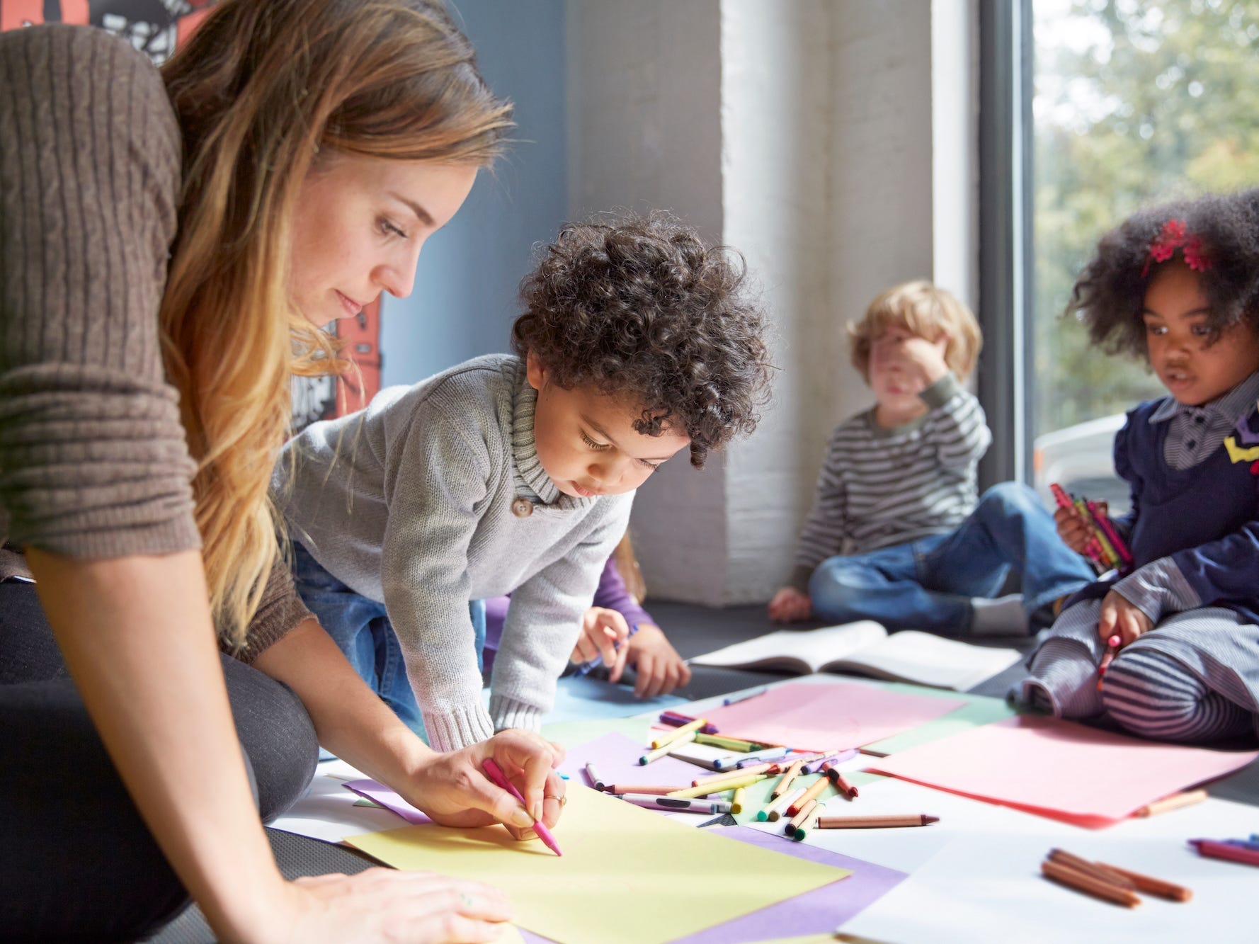 Teacher drawing with students on floor at preschool