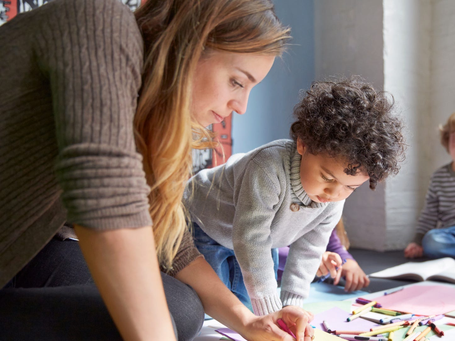 Teacher drawing with students on floor at preschool