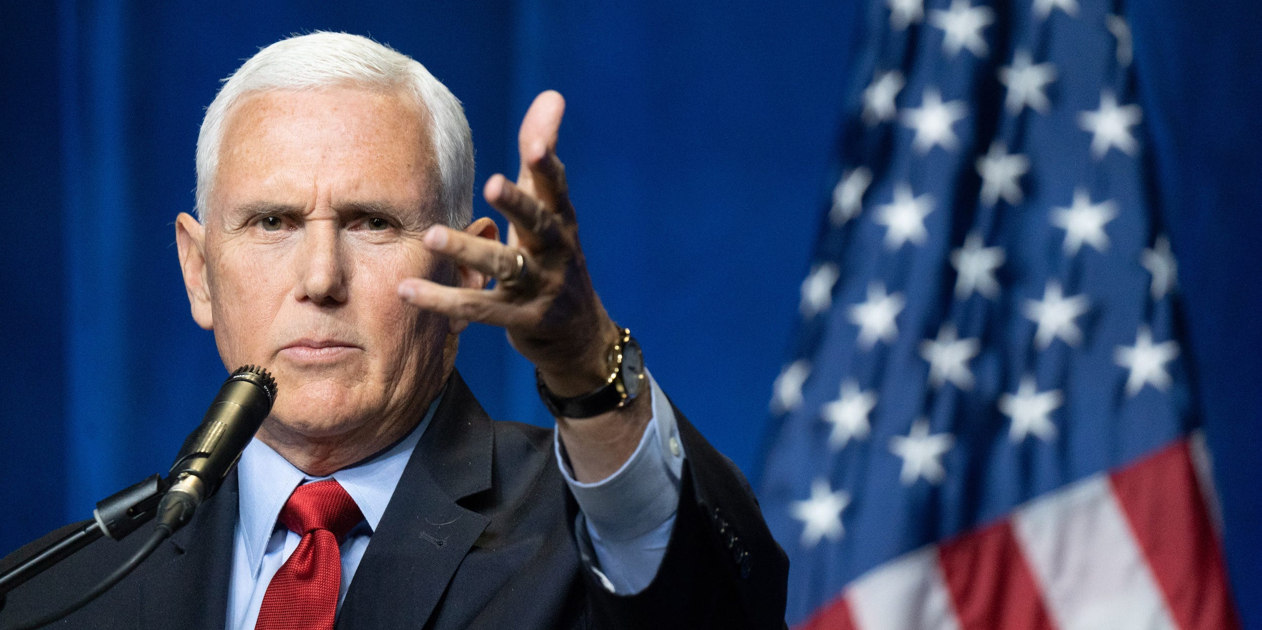 Former Vice President Mike Pence gestures forward with his open left hand tilted sideways.