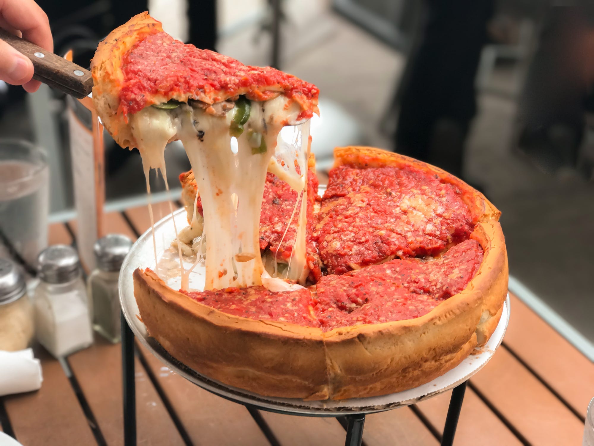 A slice of deep-dish pizza getting lifted from a platter.