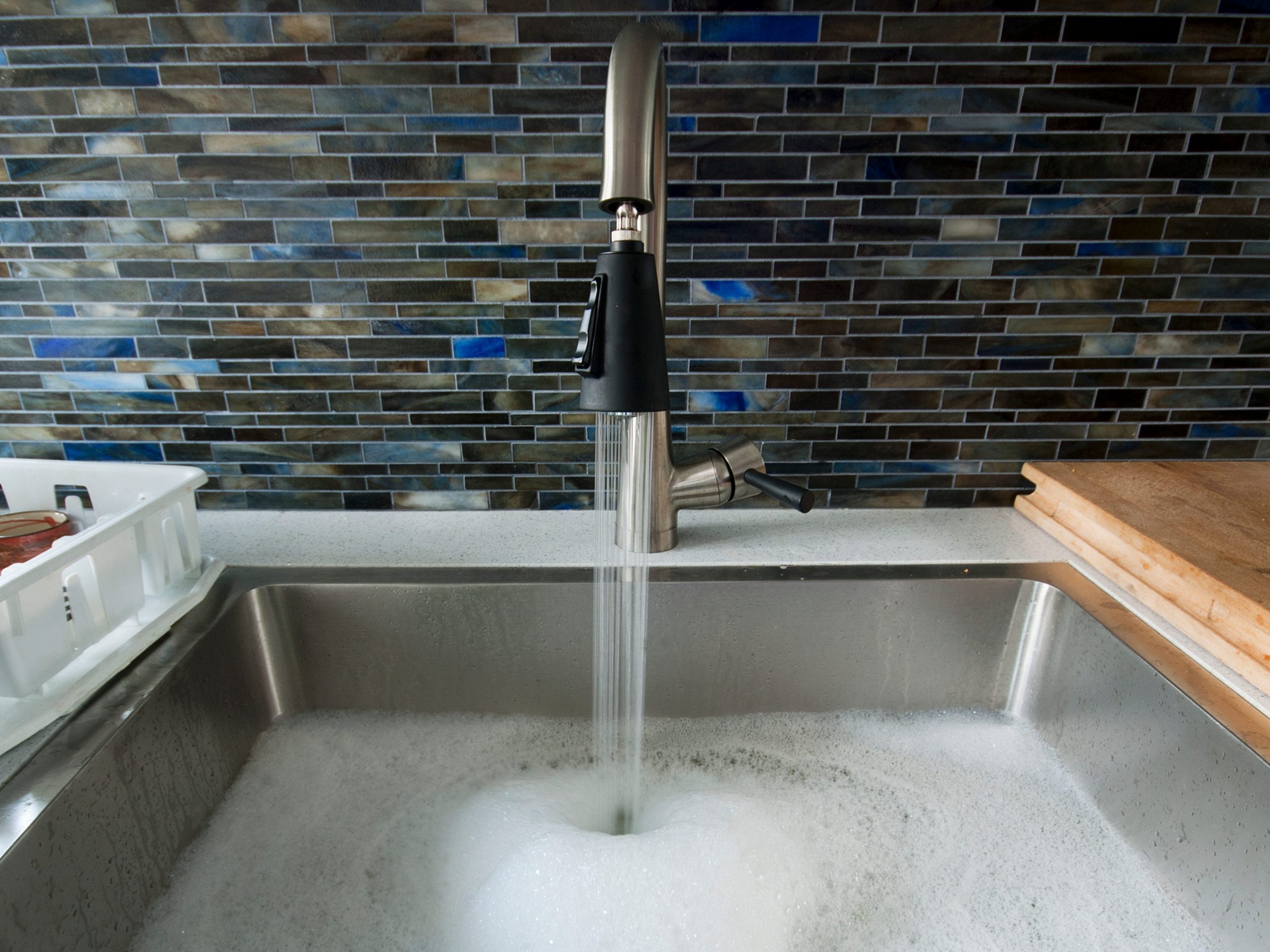 A plugged kitchen sink filled with sudsy water.