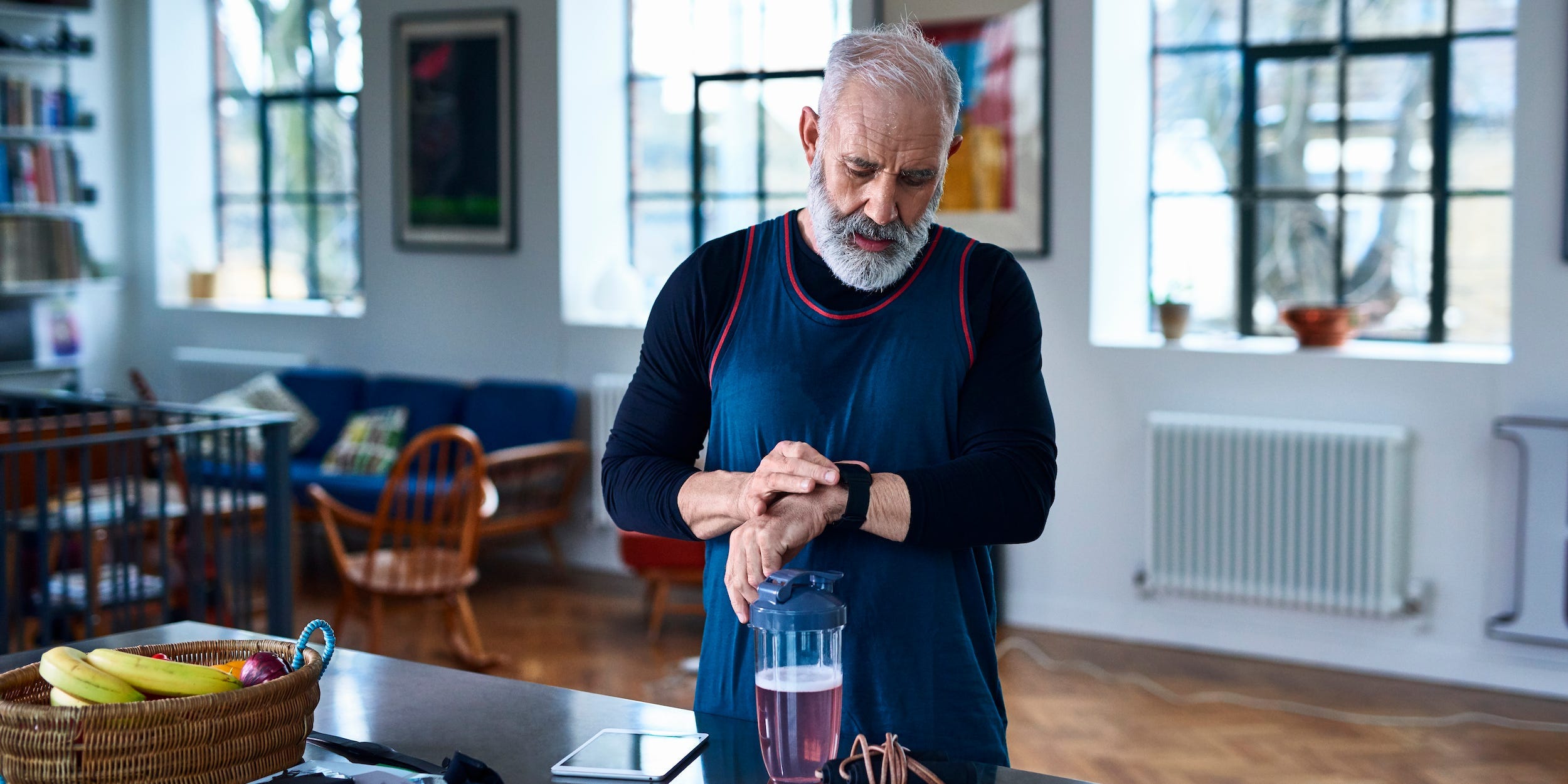 senior man looking at smart watch in kitchen at home