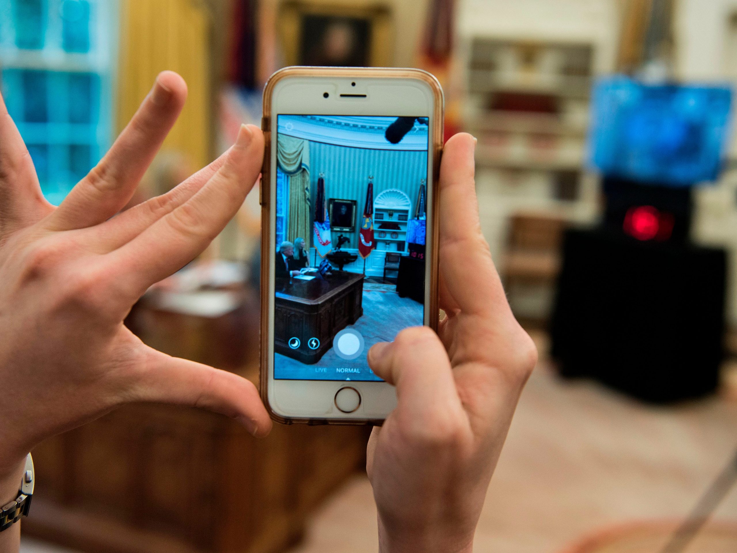 A woman uses an iPhone to take a SnapChat as former President Donald Trump speaks via video with NASA astronauts from the Oval Office of the White House on April 24, 2017.