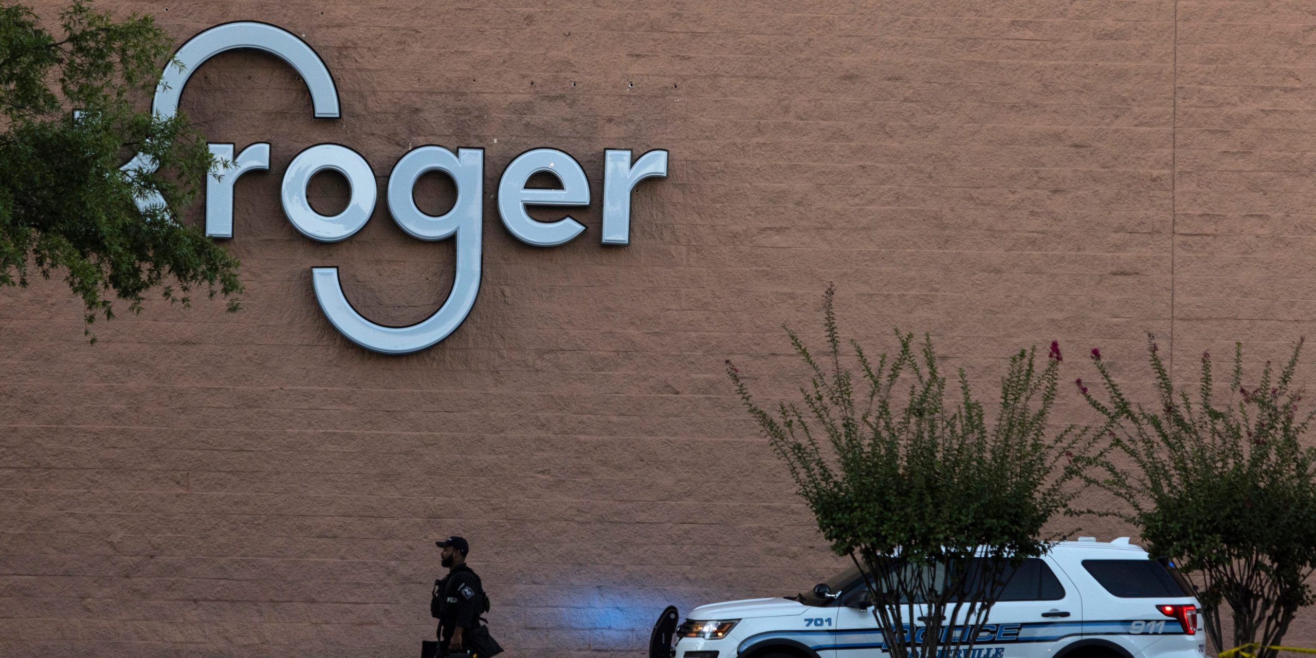 A police officer walks in front of the Kroger store.