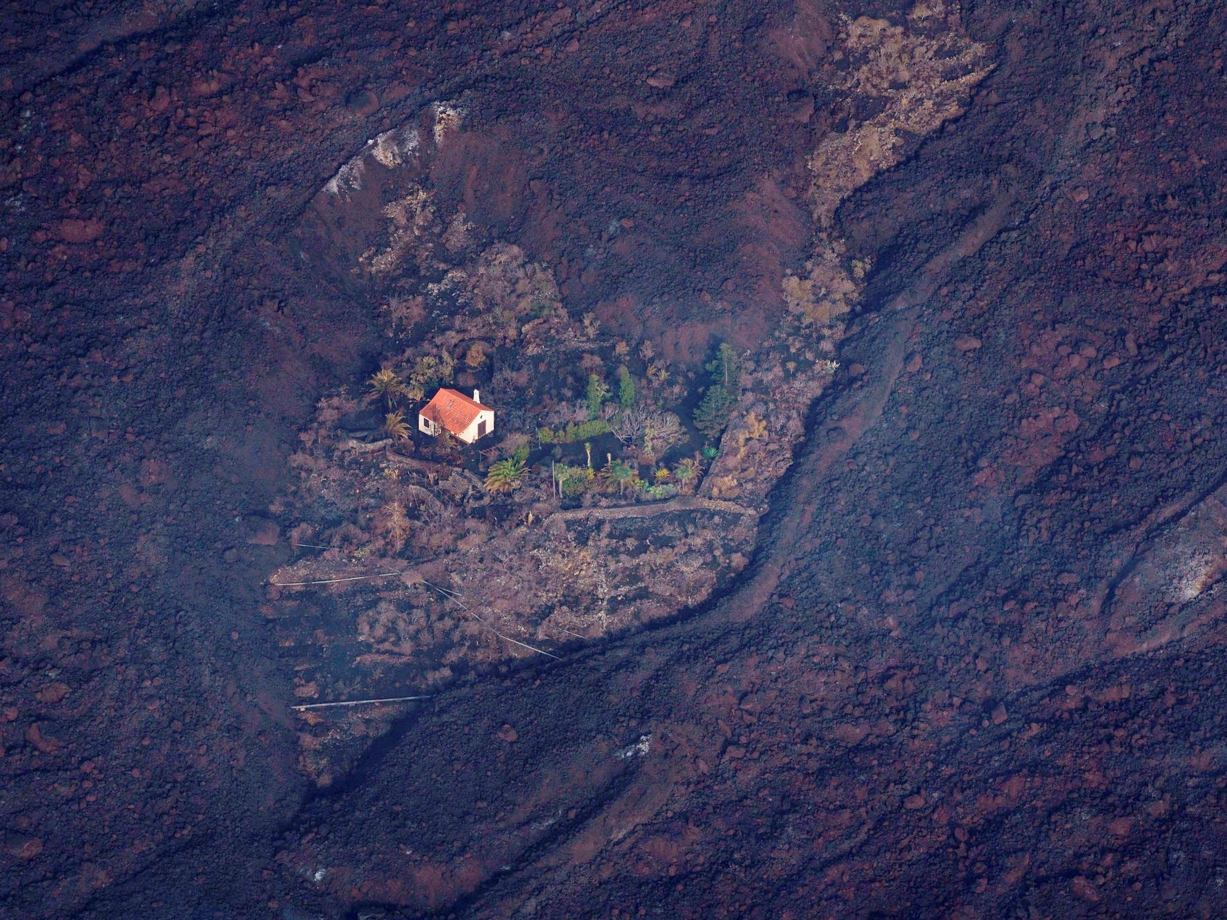 A house in the La Palma, Spain, stands alone in the side of a mountain surrounded by scorch marks.