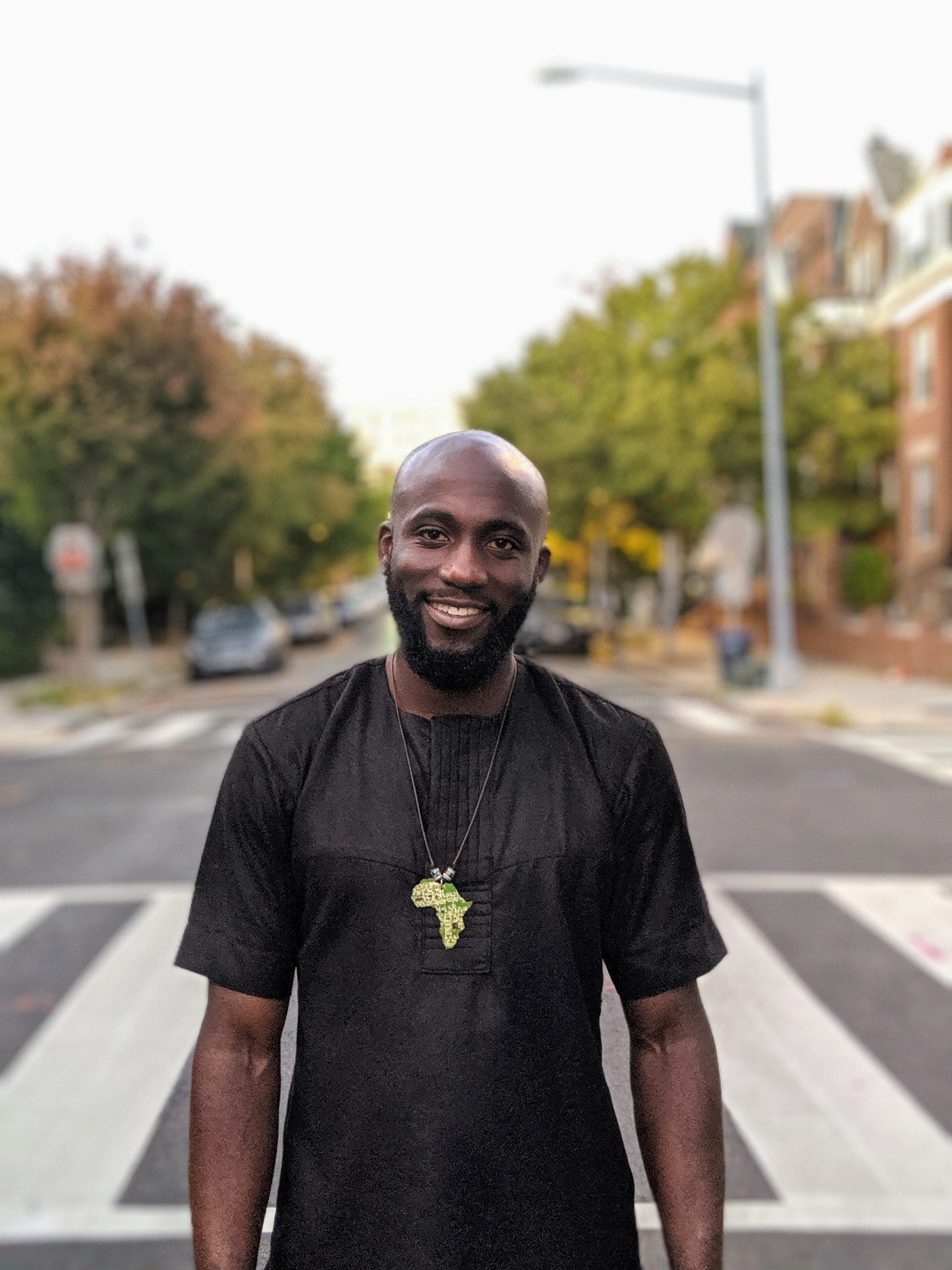 Oladosu Teyibo stands wearing a black shirt in the middle of the street smiling