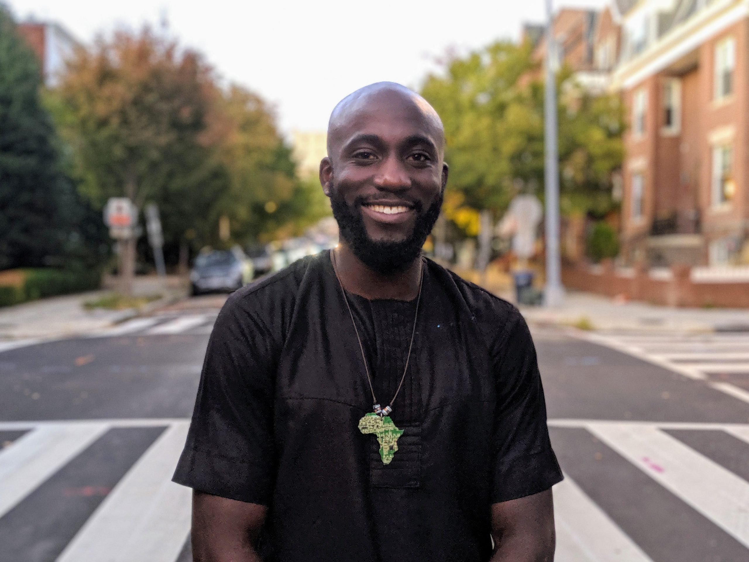 Oladosu Teyibo stands wearing a black shirt in the middle of the street smiling
