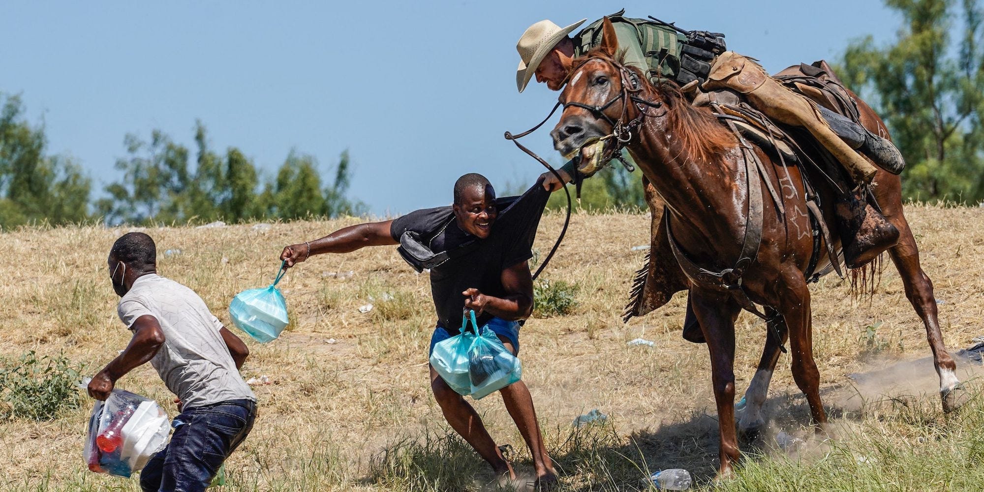 A US Border Patrol agent on horseback grabbing a Haitian migrant.