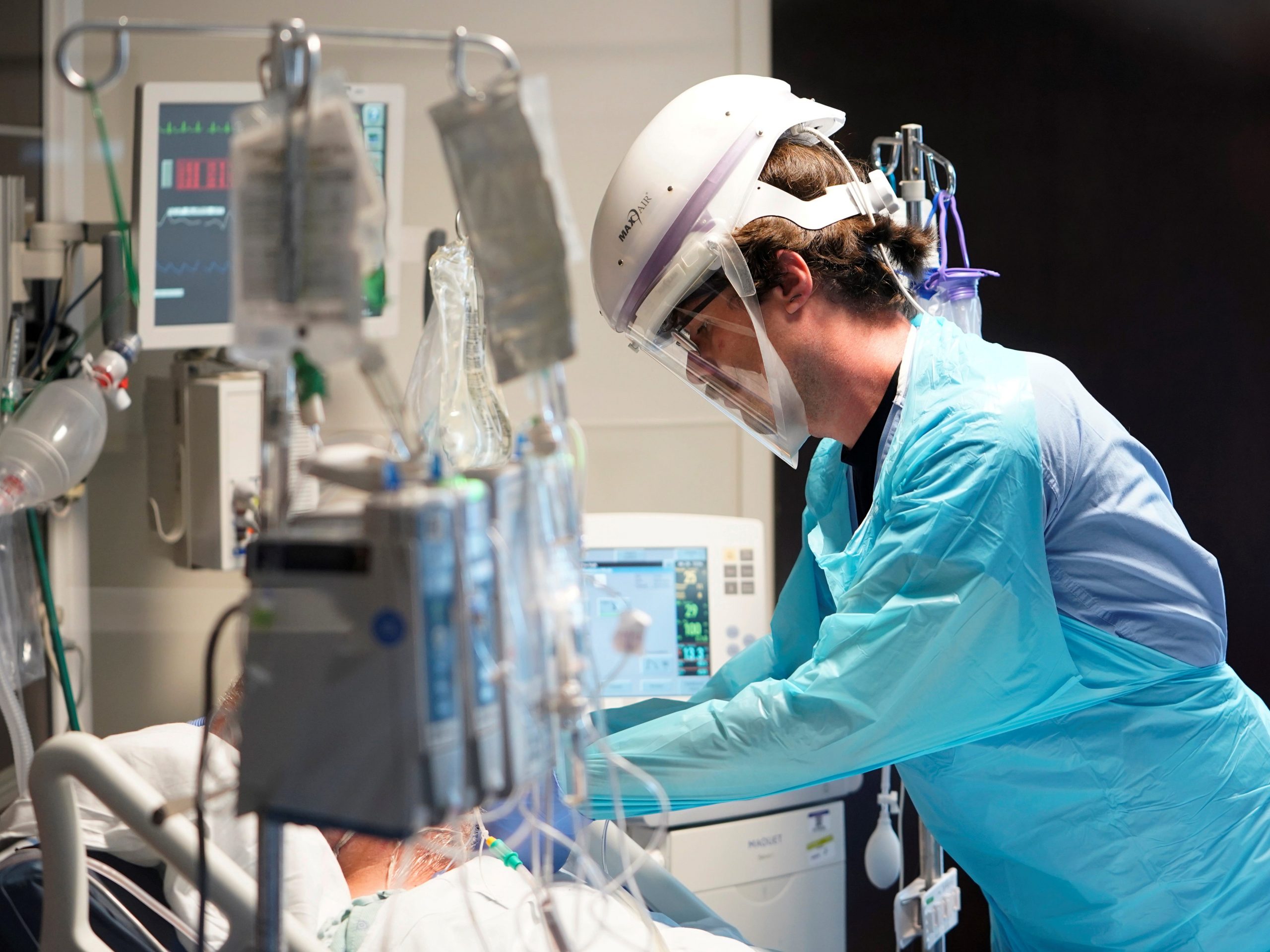 A nurse wearing ppe tends to a COVID-19 patient in an icu