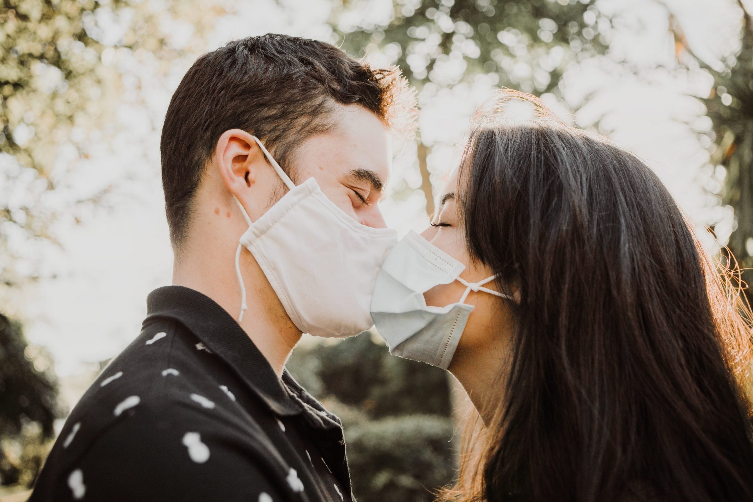 A man and a woman kissing through their masks