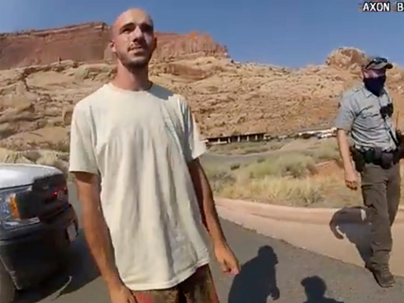 Brian Laundrie in the desert with a cop behind him