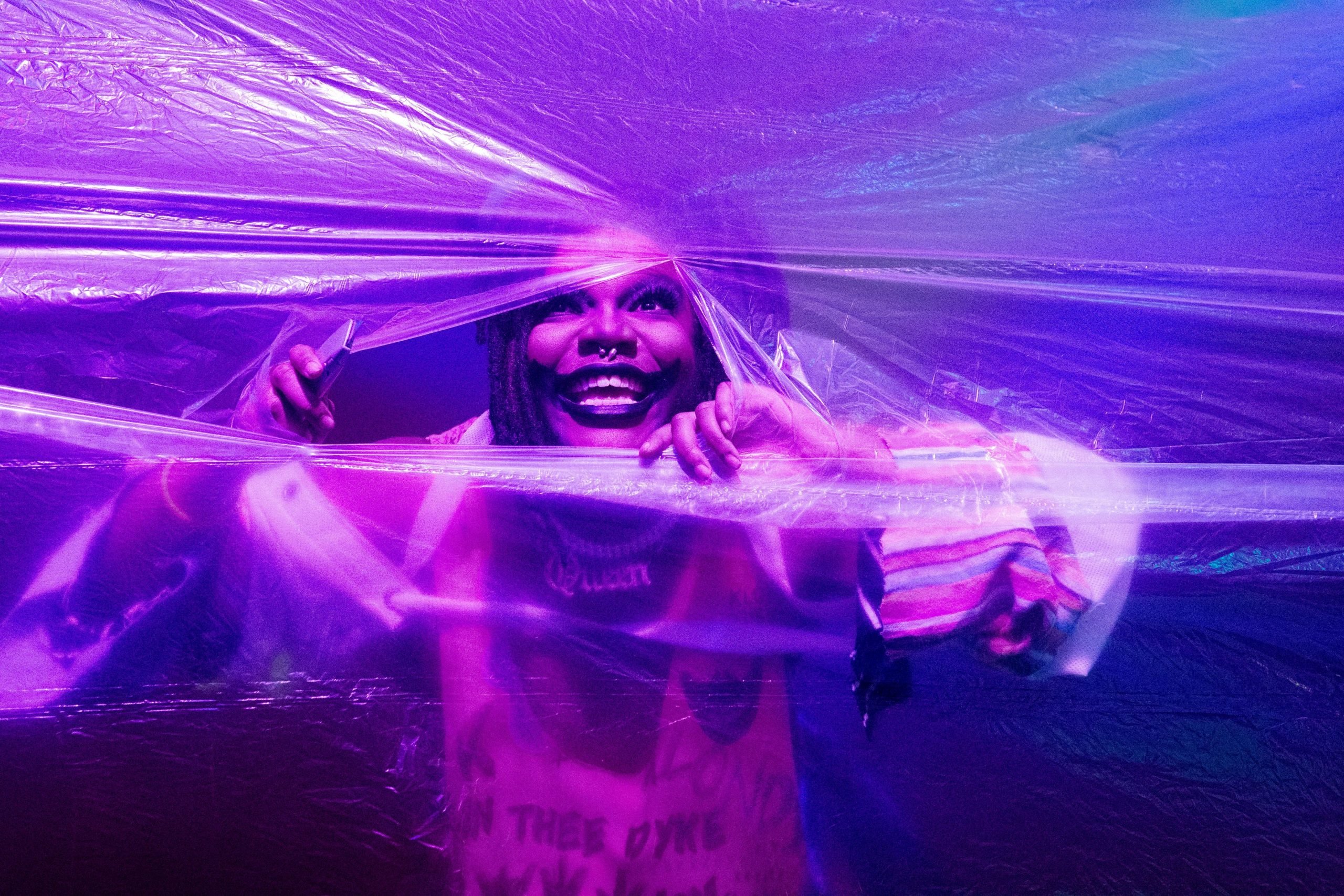 A performer pushes through a wall of plastic.