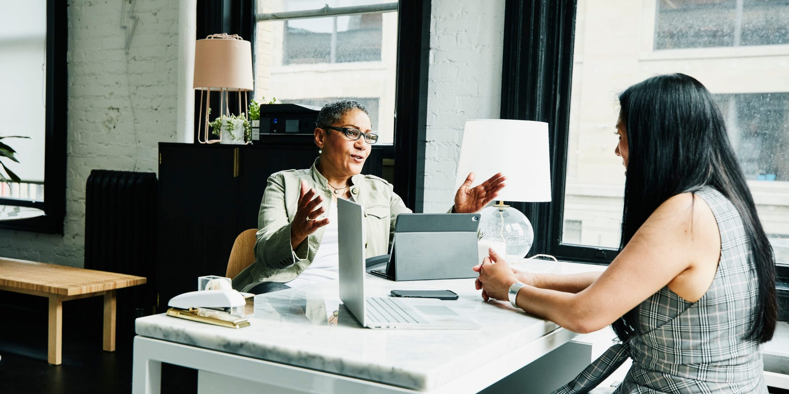 Female financial advisor in discussion with a female business owner at a desk in an office.
