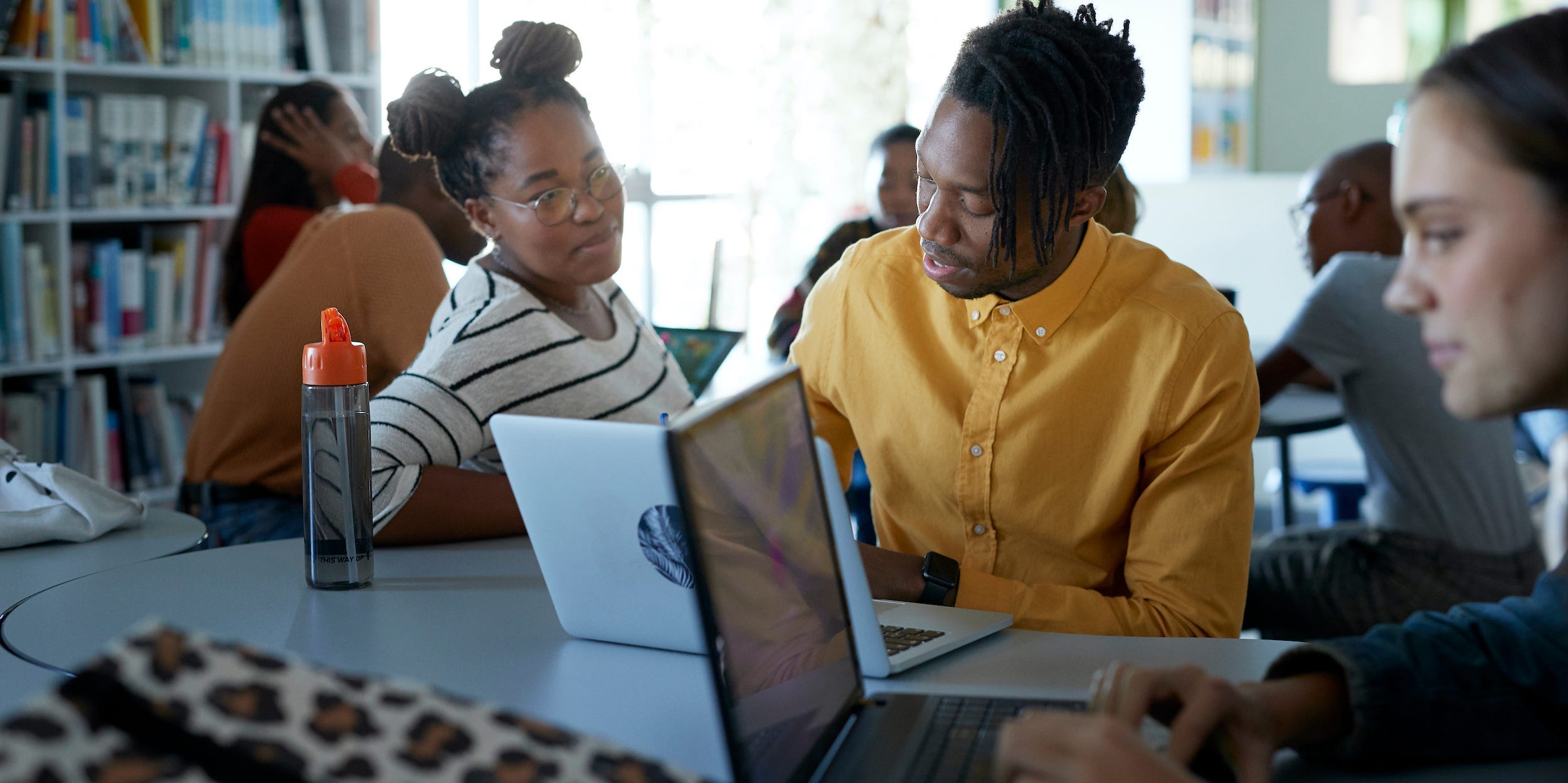 students working together on laptops in library