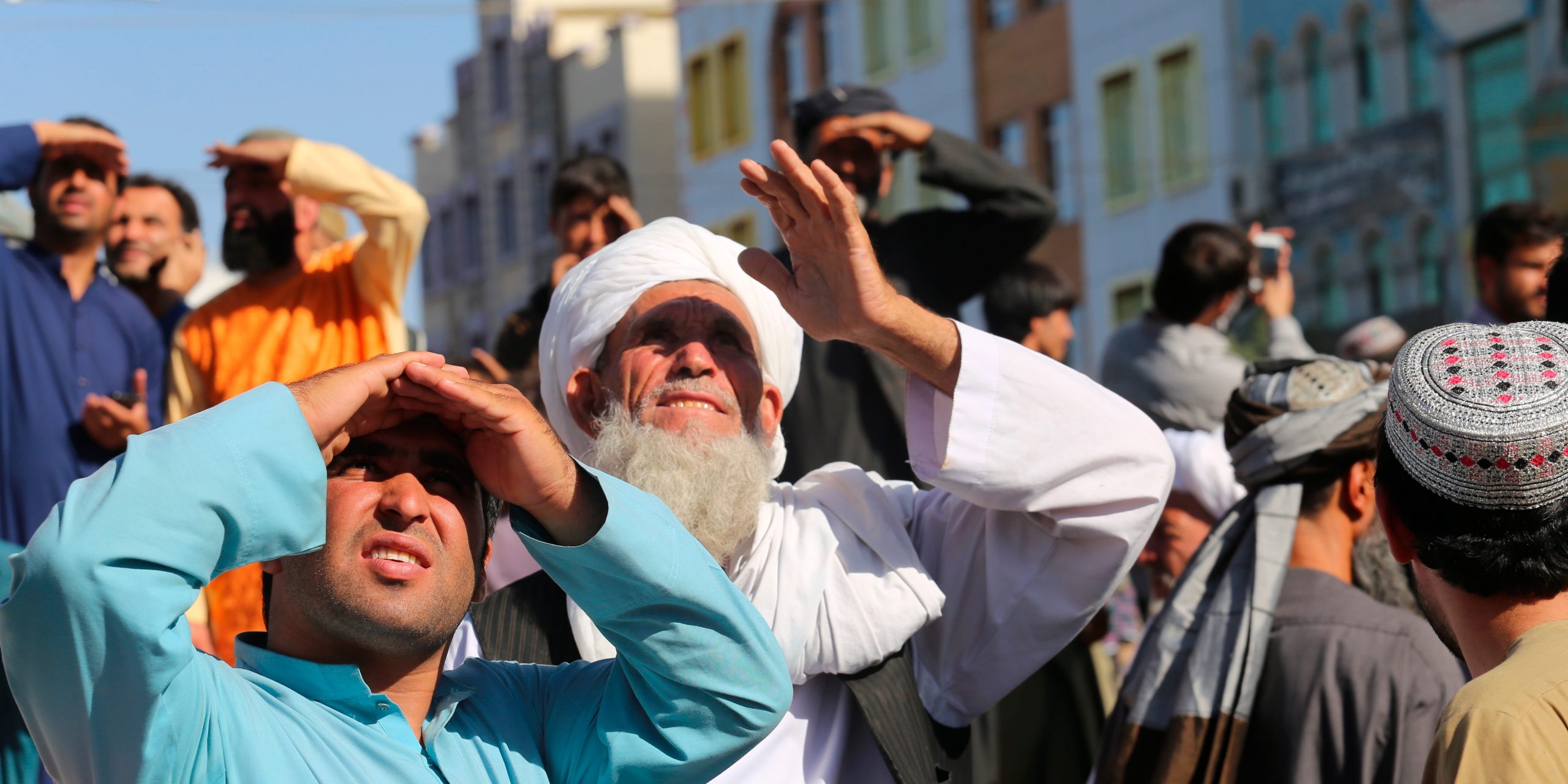 People in Herat, Afghanistan, look up at a body hung from a crane