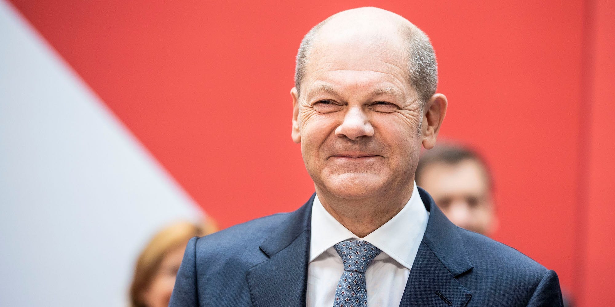 Olaf Scholz, wearing a suit and carrying a bouquet of flowers smiles after his party, the SPD, gathered the most votes in Germany's preliminary elections  results