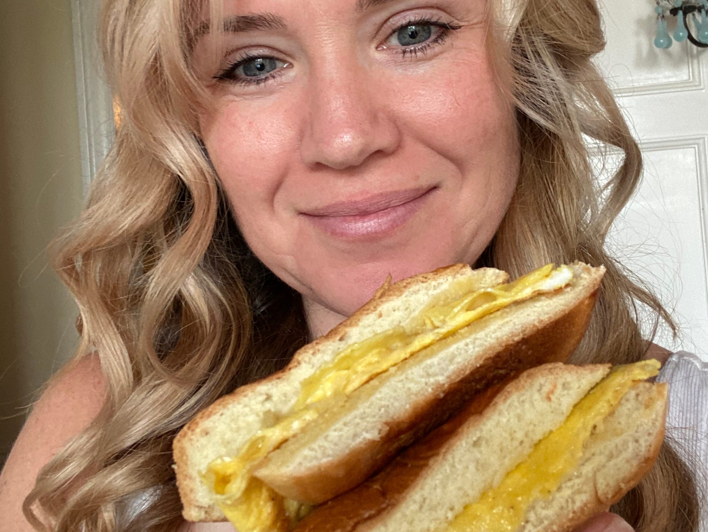 cholding up an egg sandwich.