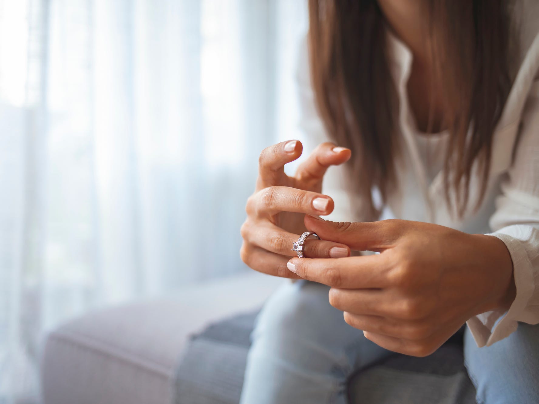 A woman twists her engagement ring indicating she is stressed out about wedding planning.