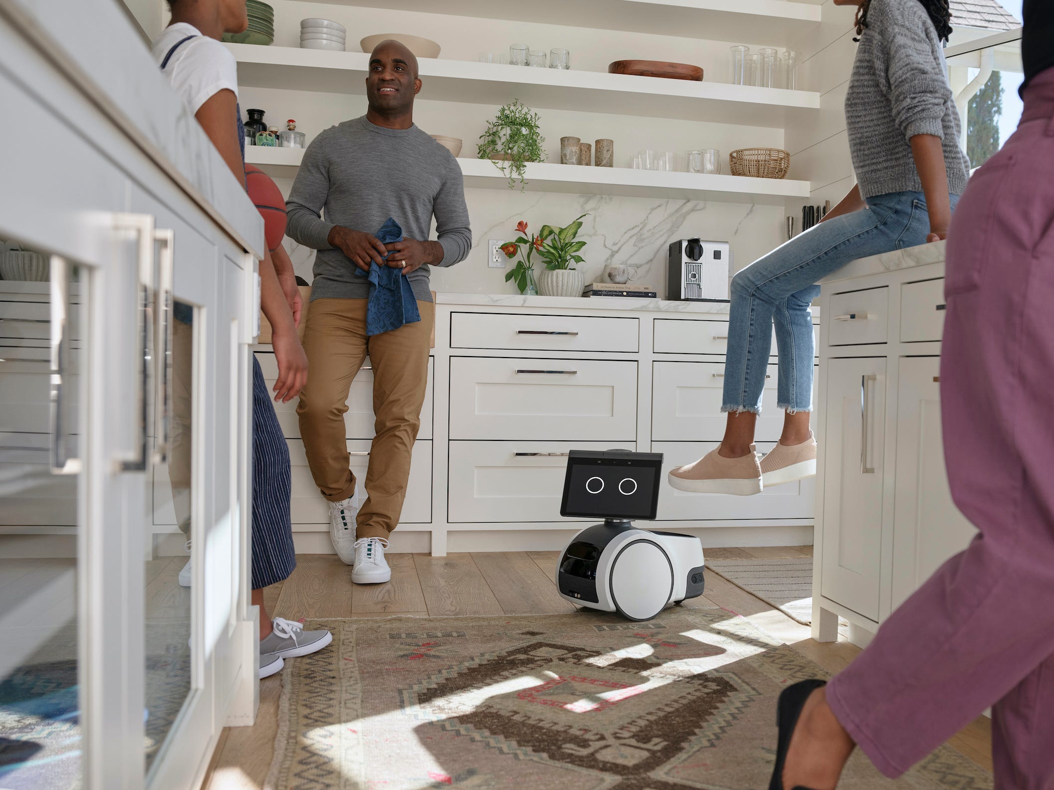 Amazon Astro robot on kitchen floor surrounded by people talking