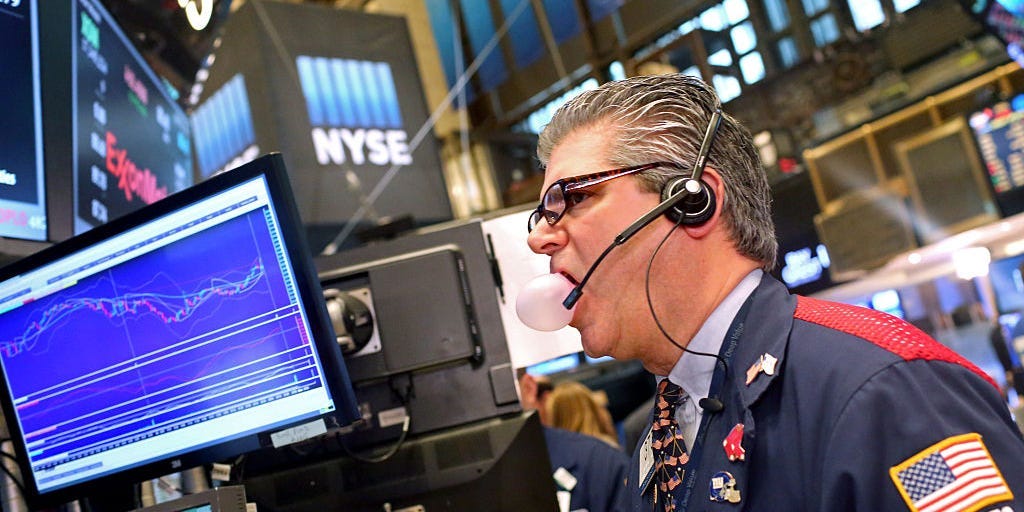 A trader blows out a chewing gum bubble while working on the floor of the New York Stock Exchange