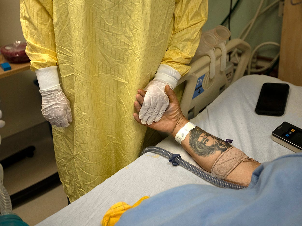 A registered nurse holds hand of a COVID patient in Martin Luther King, Jr. Community Hospital in Los Angeles.