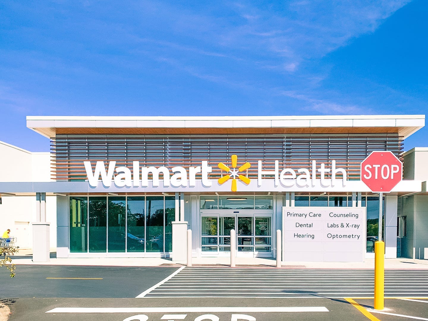 A building with a sign out front that says Walmart Health and a parking lot