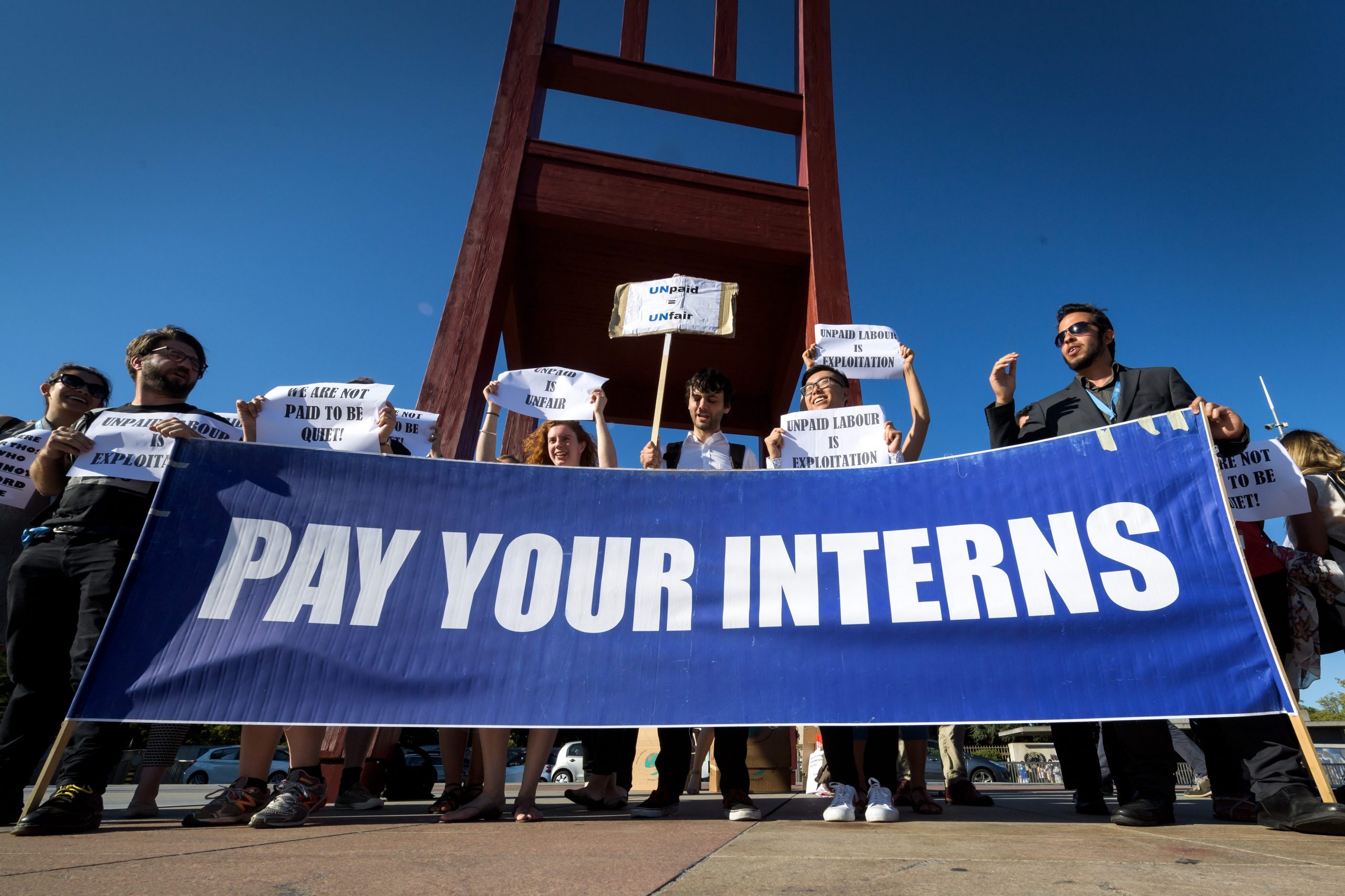 Unpaid interns at the United Nations (UN) in Geneva hold a banner during demonstration.