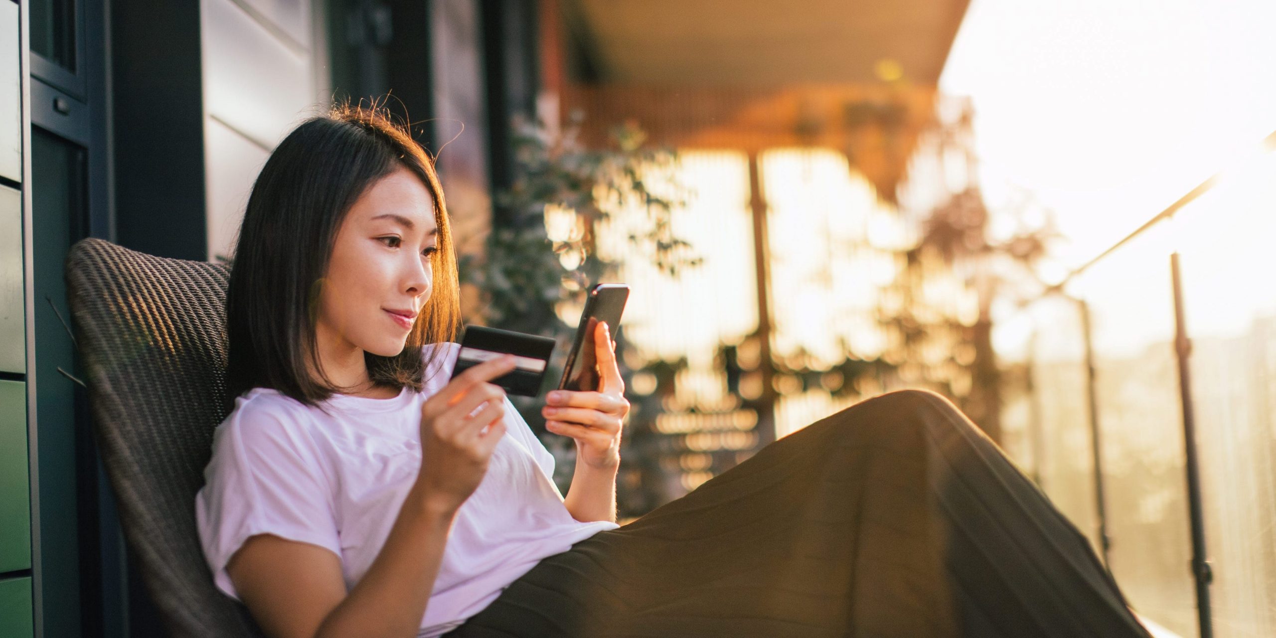 Young woman shopping online with smart phone and credit card in hand.