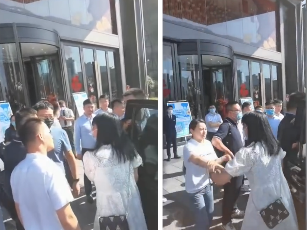 In een op Weibo geplaatste video, is te zien hoe een vrouwelijke belegger (in een witte jurk, R) zich vastklampt aan de deur van een personenauto buiten een kantoorgebouw van Evergrande, terwijl werknemers van het bedrijf proberen haar uit het gebouw te houden. Foto: Screenshot/Weibo
