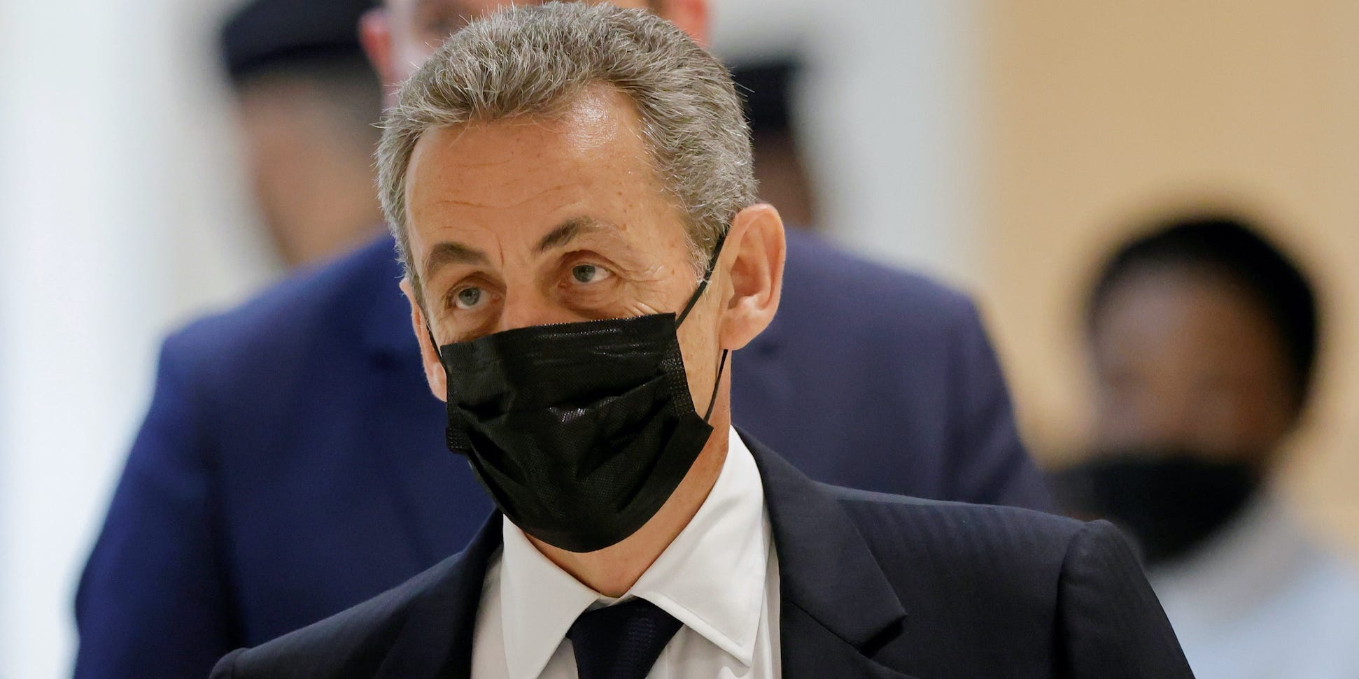 Nicolas Sarkozy wearing a suit and a face mask