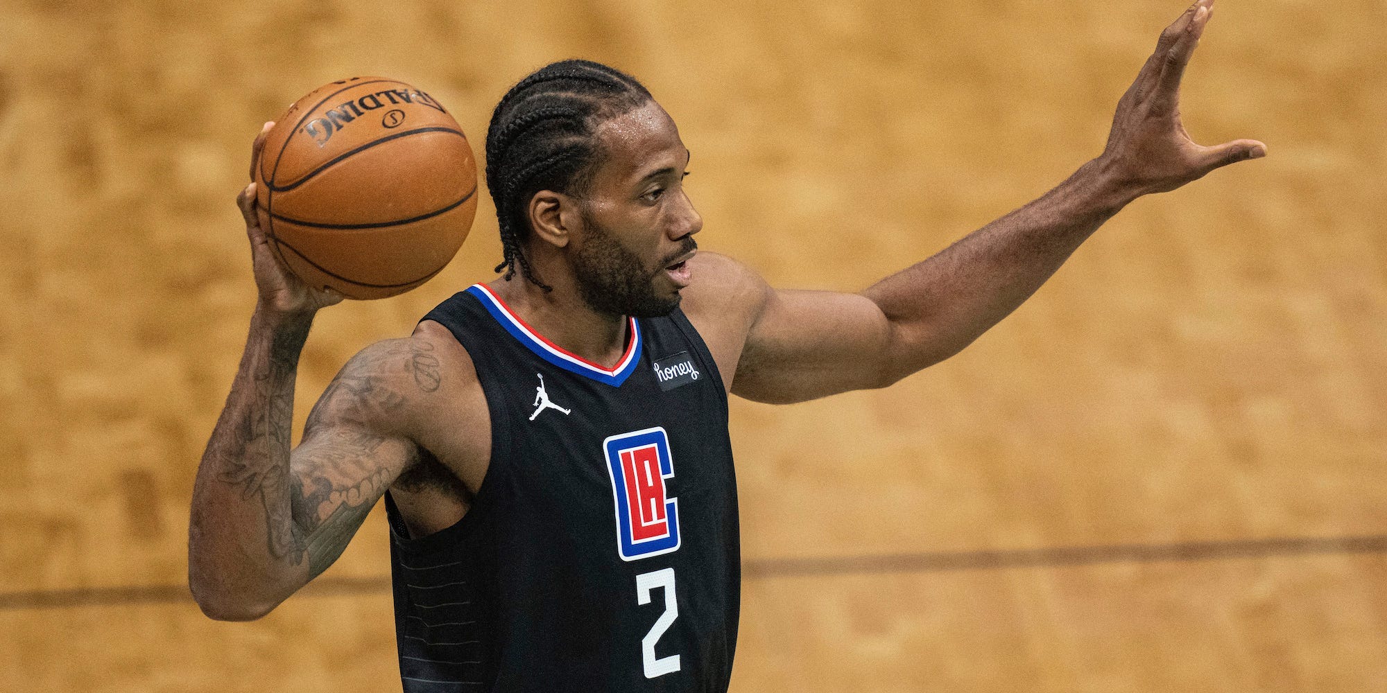 Kawhi Leonard holds a basketball in one hand and looks to make a pass.