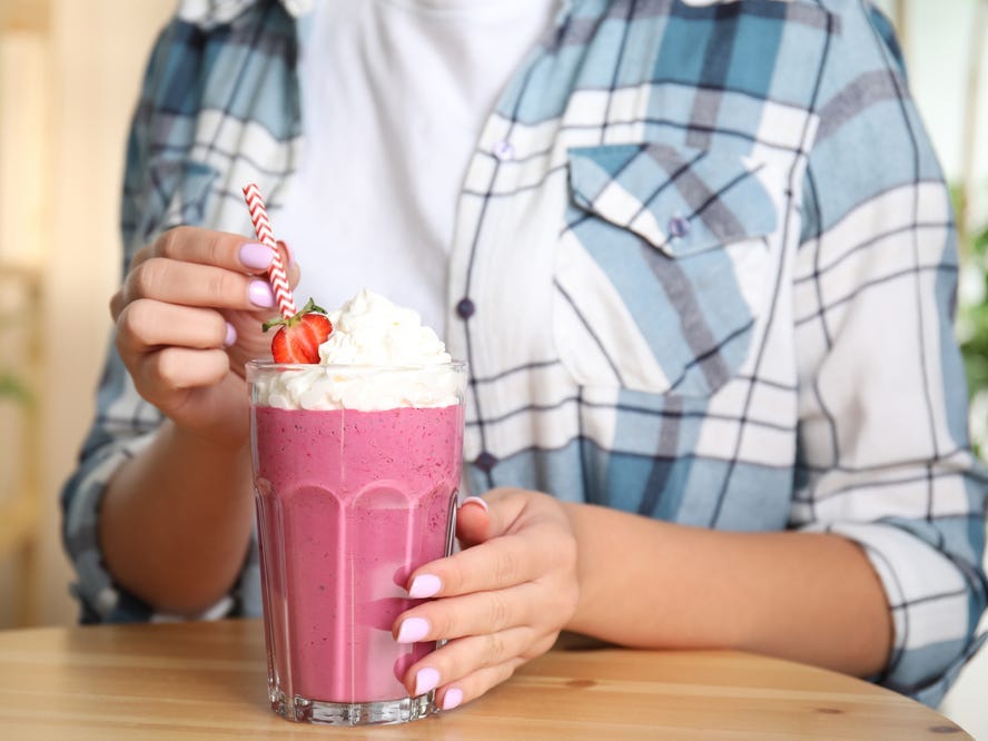 Someone holding a strawberry milkshake.