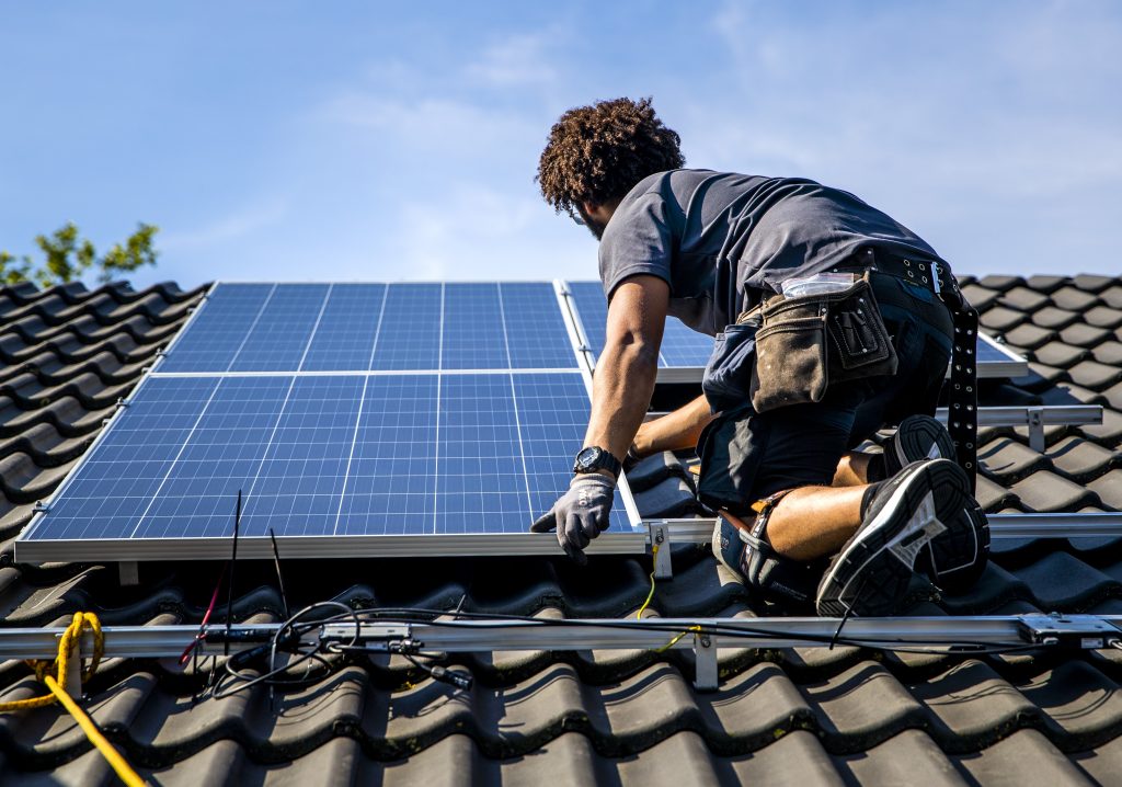 Een installateur plaatst zonnepanelen op het dak van een woonhuis in Gouda.