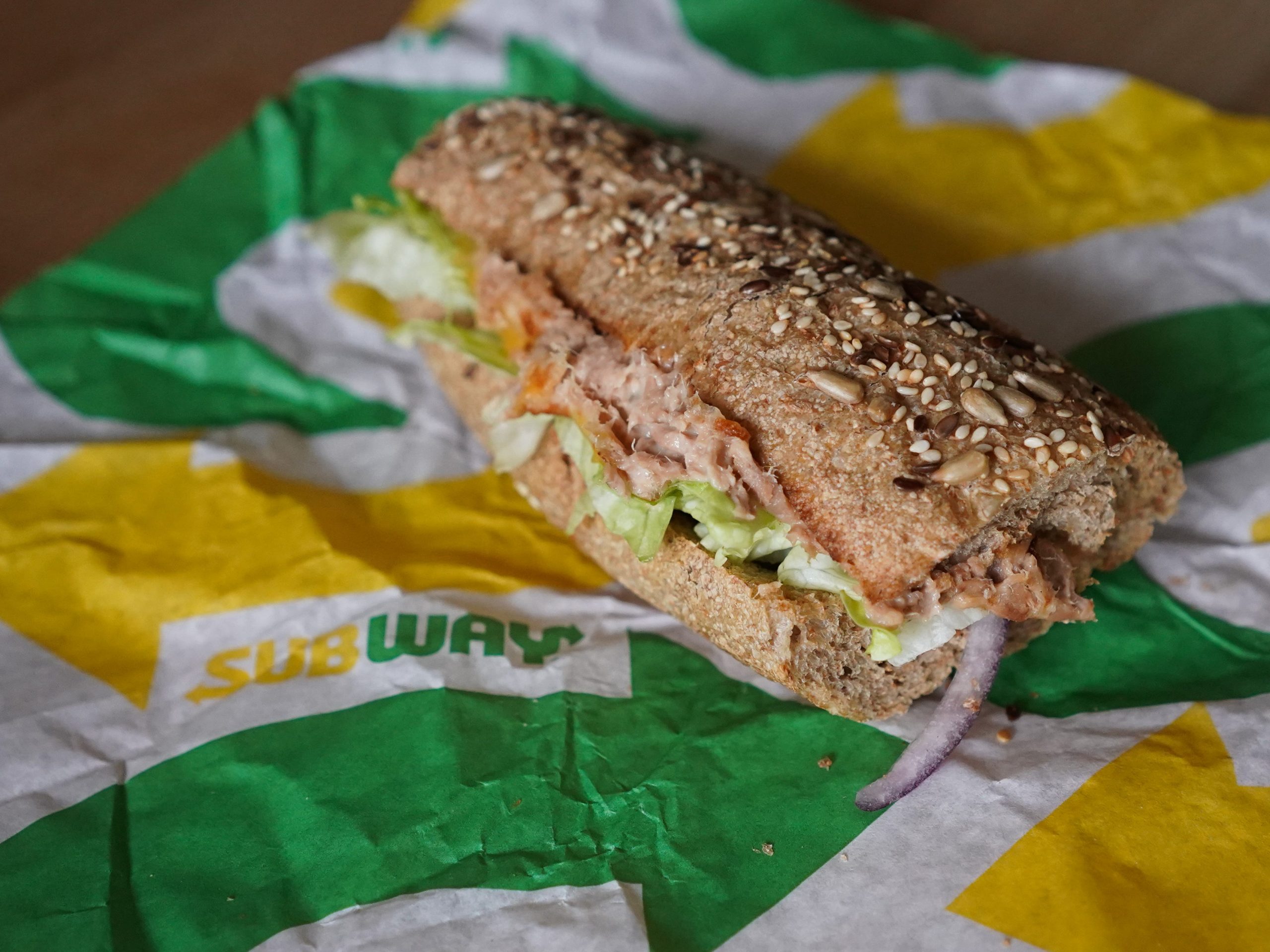 tuna sandwich with lettuce and tomato on wrapper paper